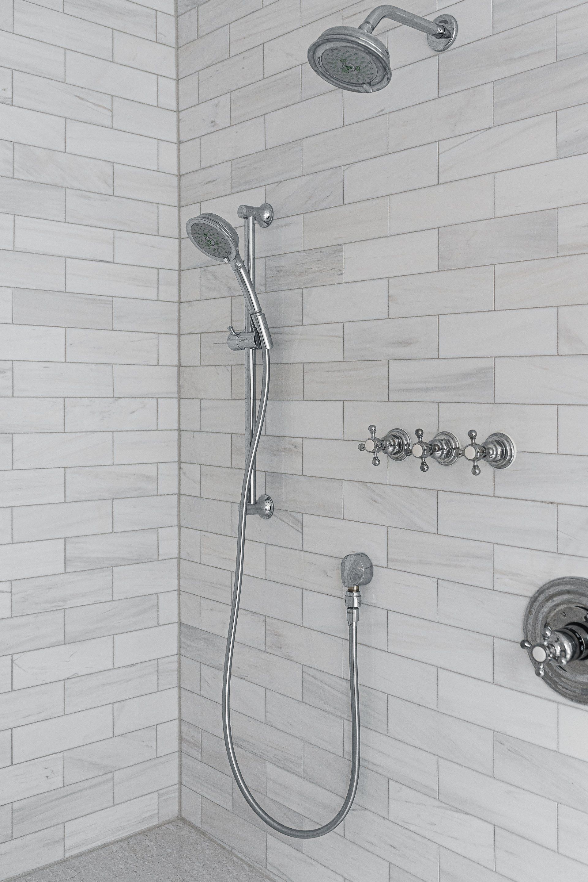 A shower with two shower heads and a hose attached to it