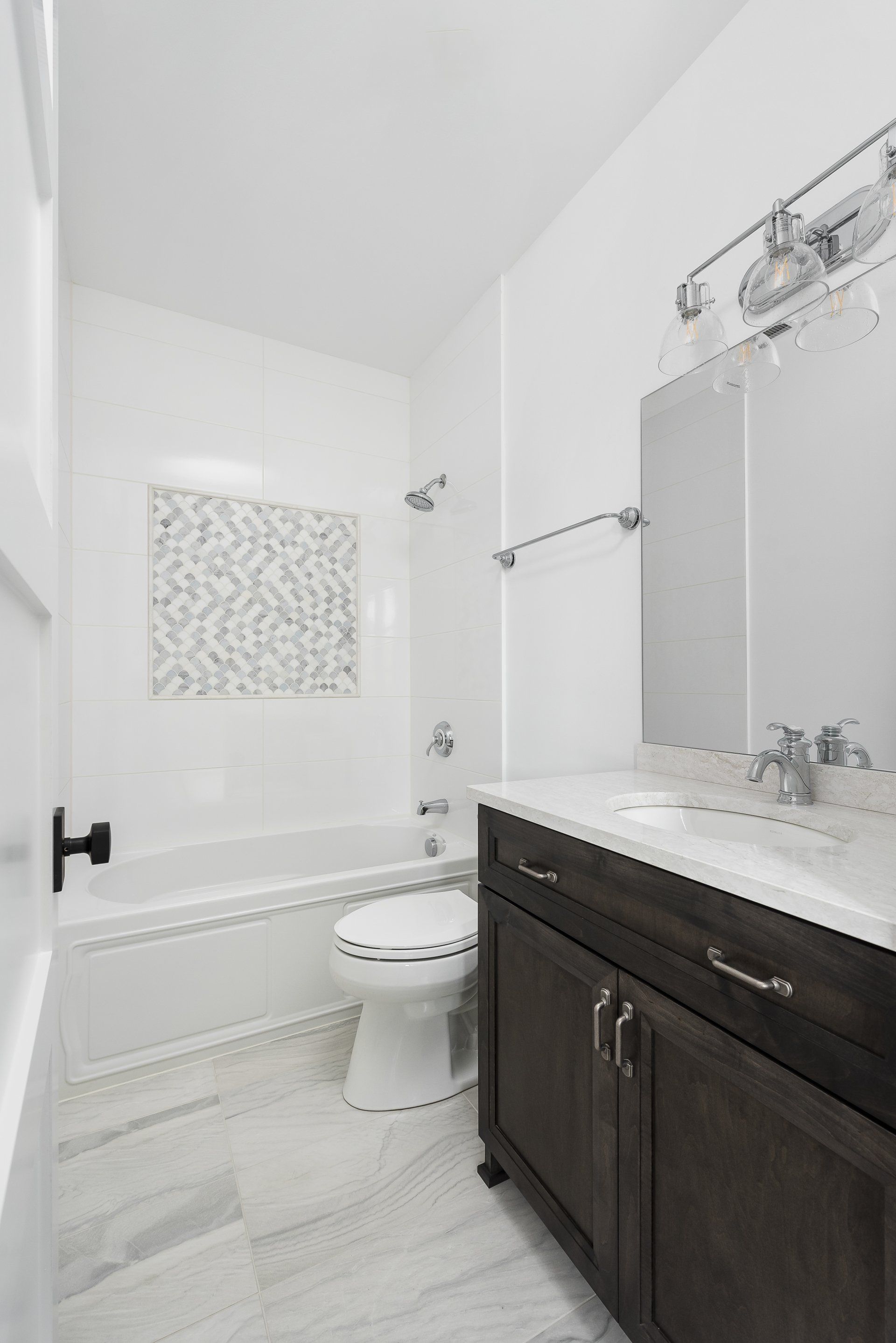 A bathroom with a toilet , sink , bathtub and mirror.