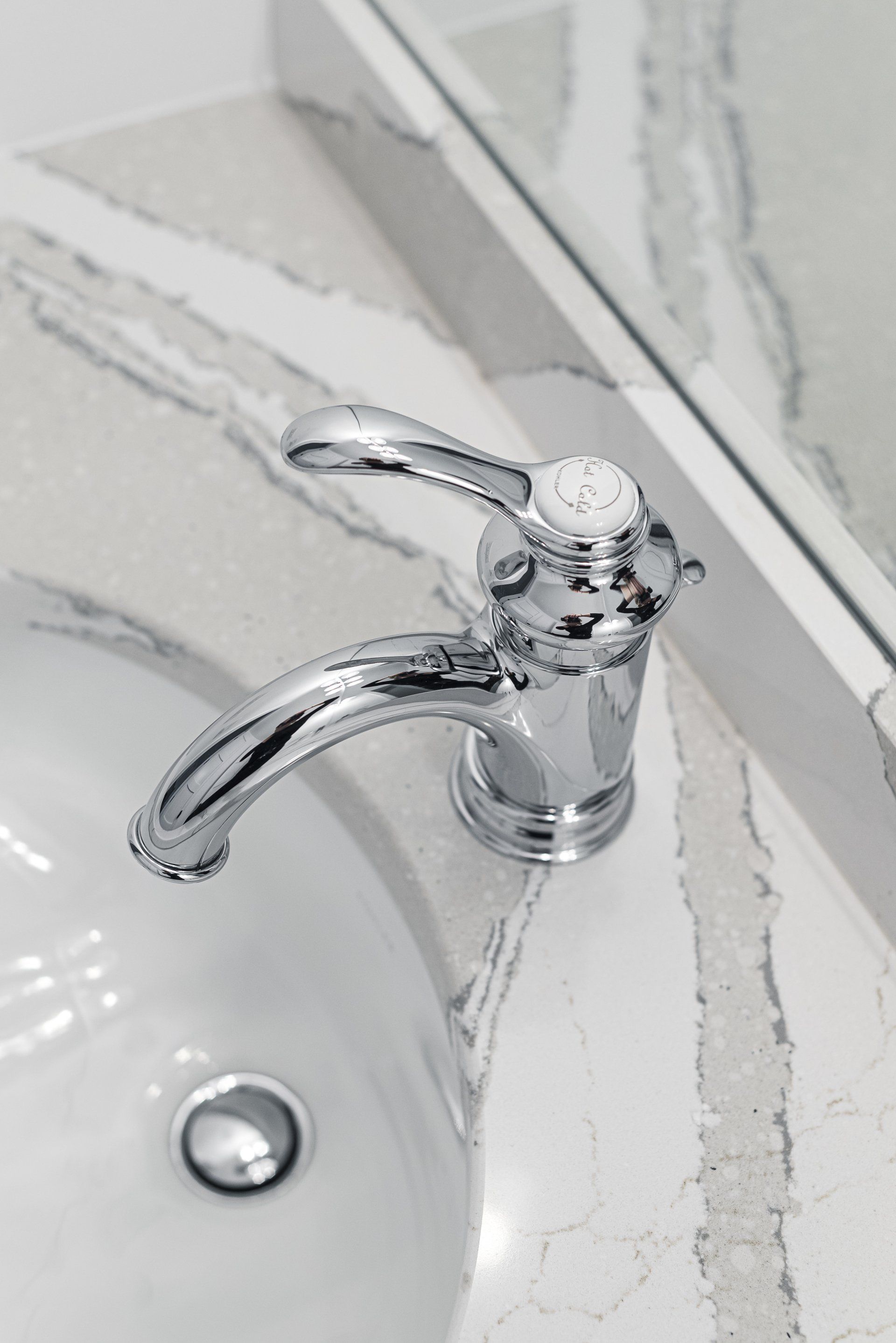 A bathroom sink with a chrome faucet and a mirror.