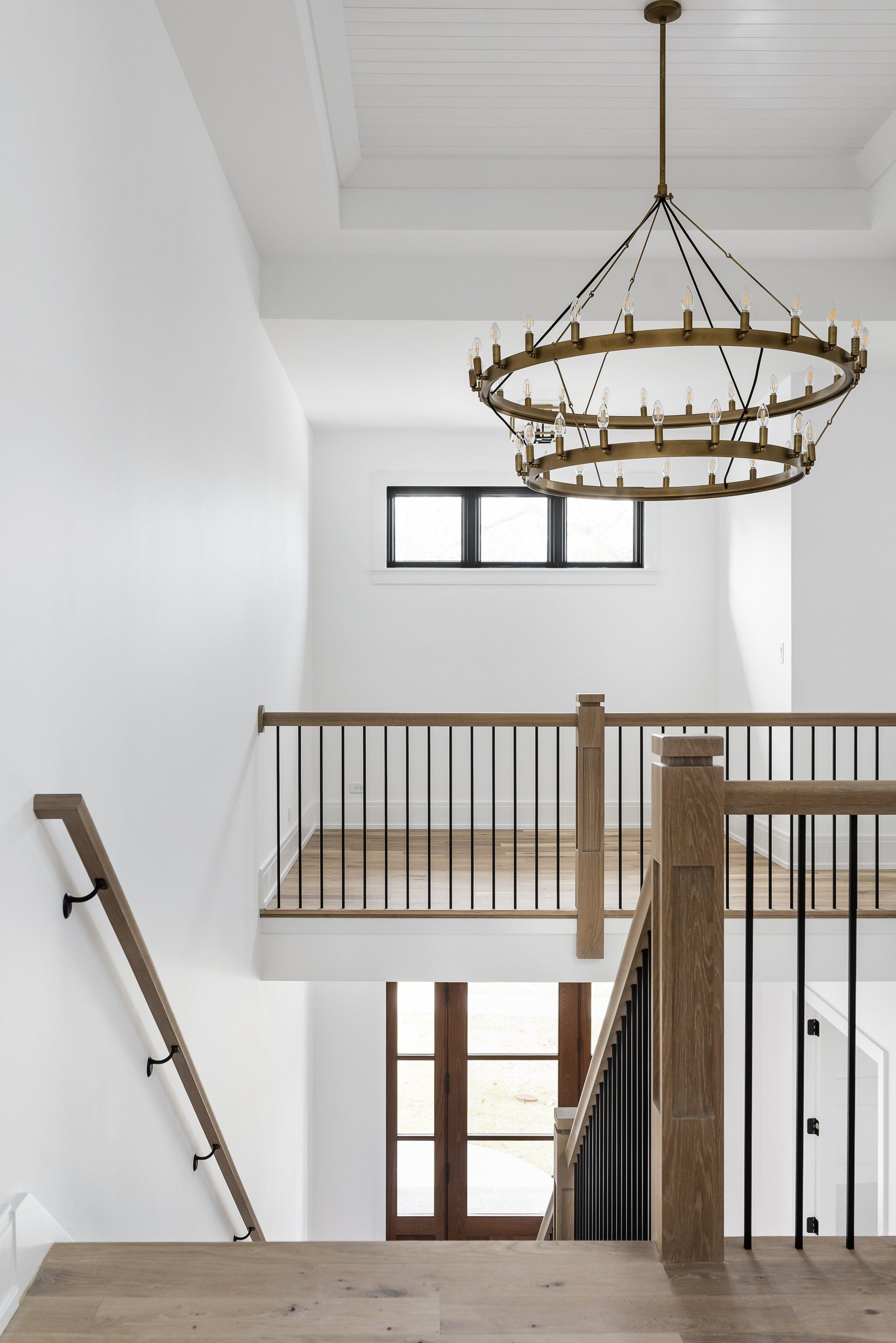 A staircase with a wooden railing and a chandelier hanging from the ceiling.