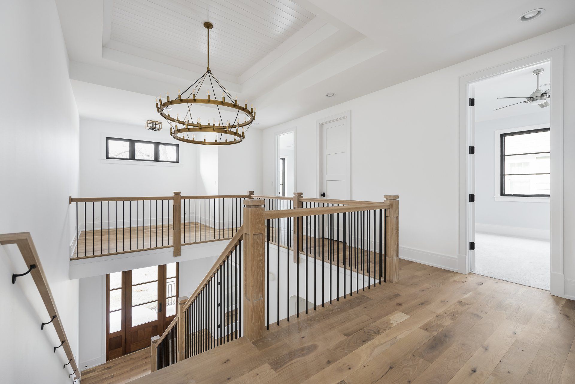 A staircase in a house with a wooden railing and a chandelier hanging from the ceiling.