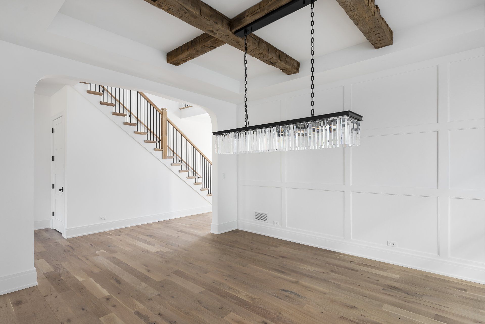 An empty dining room with a staircase and a chandelier hanging from the ceiling.