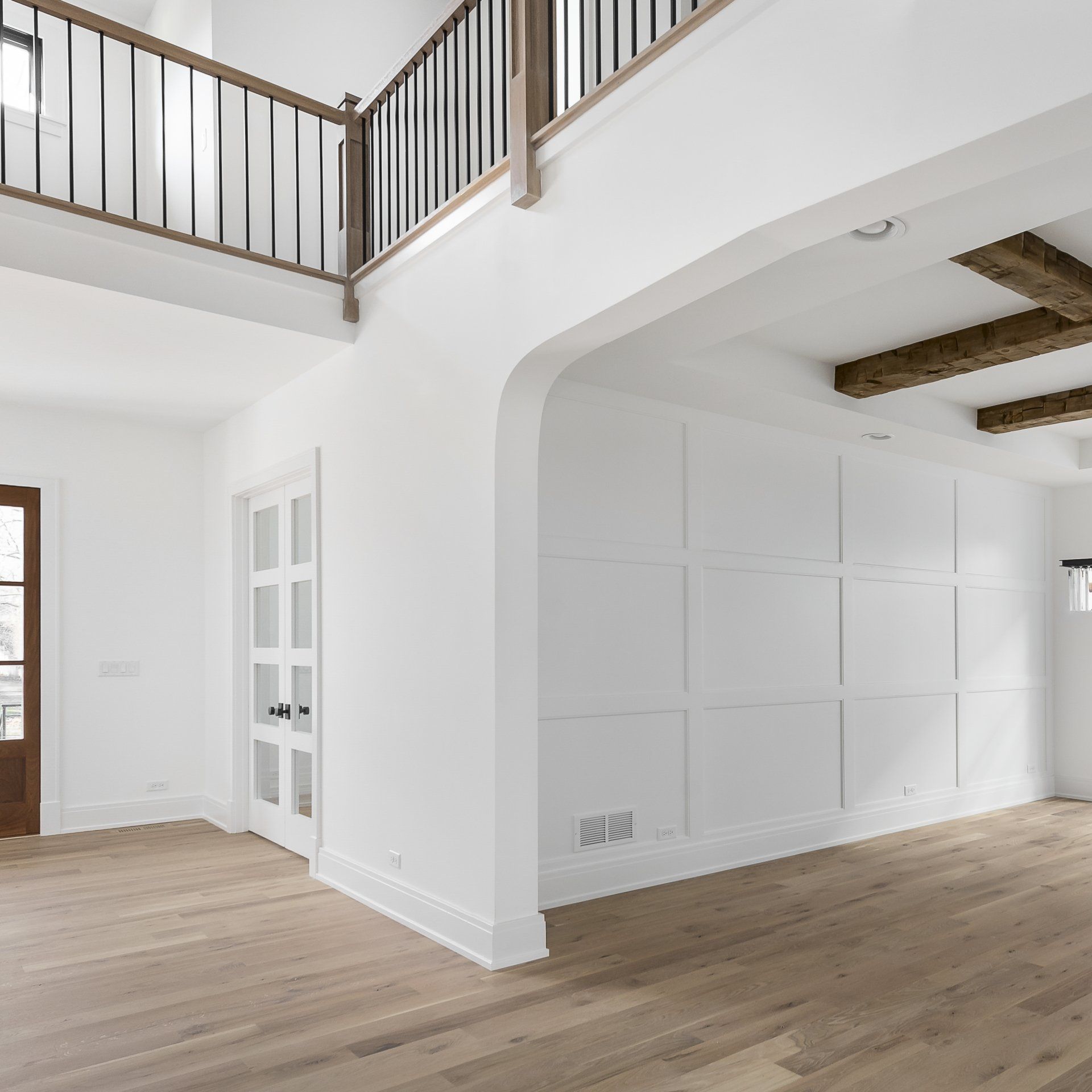 A living room with white walls and wooden floors and a balcony.