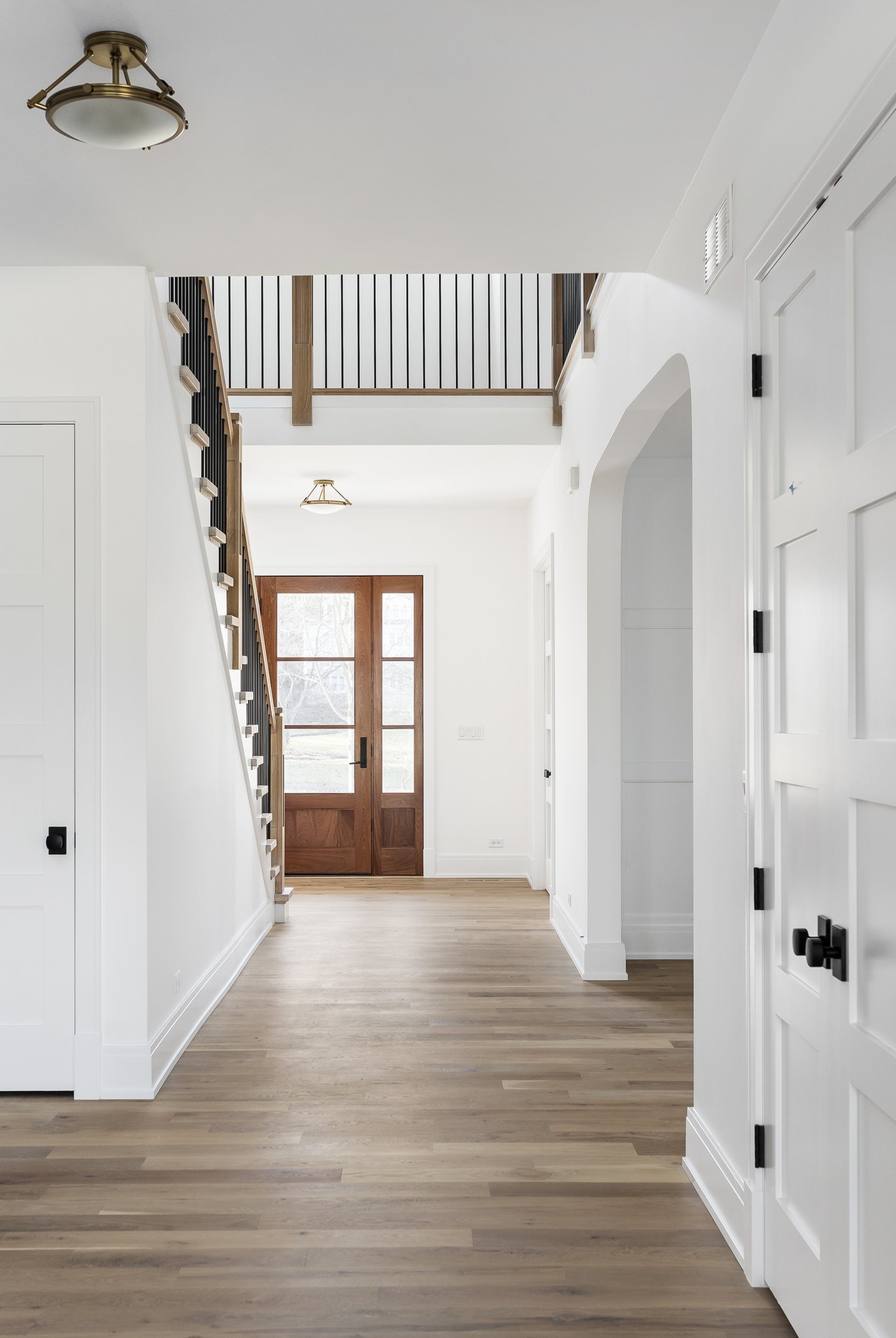 A hallway in a house with a wooden door and stairs.