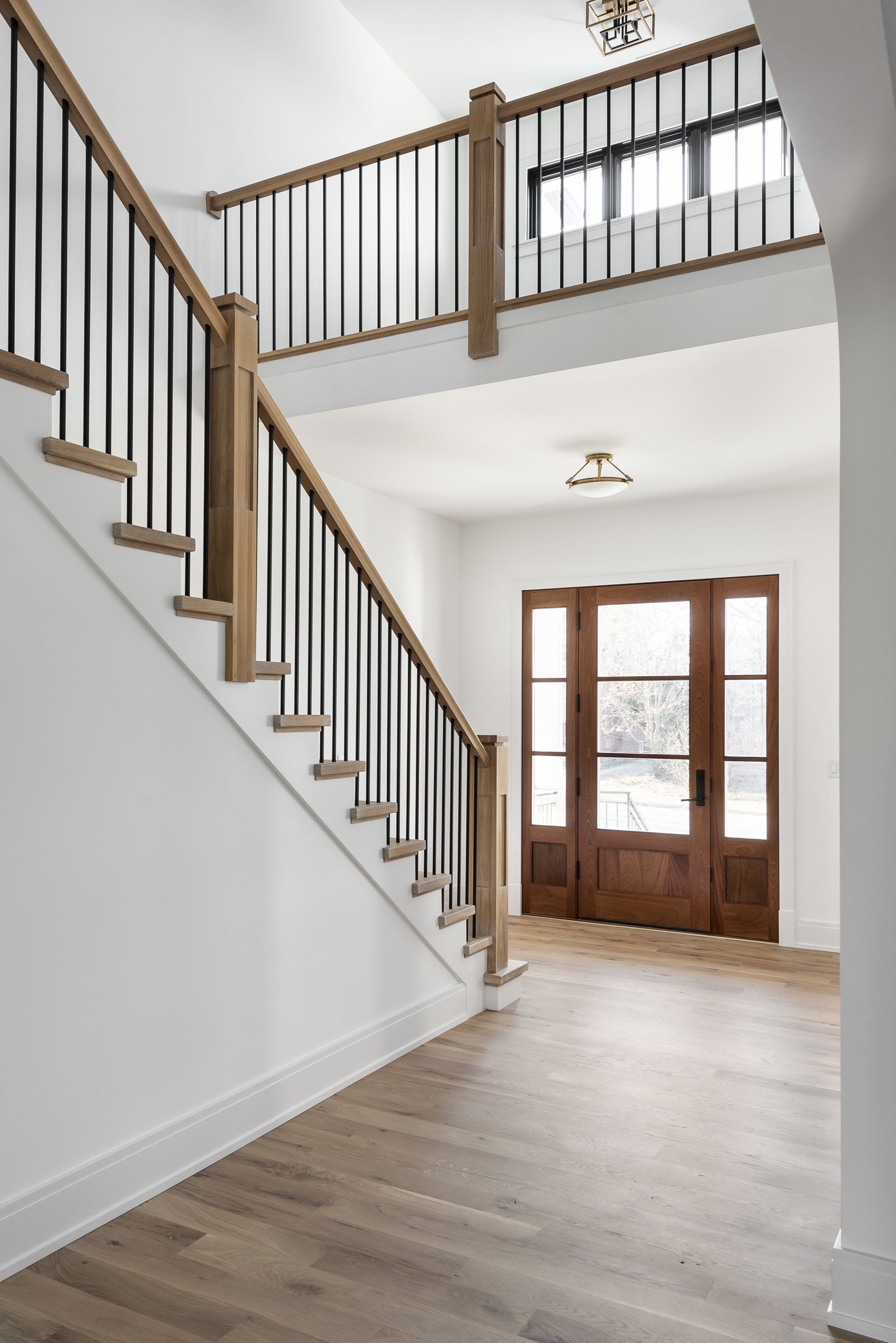 An empty hallway with a wooden staircase and a wooden door.