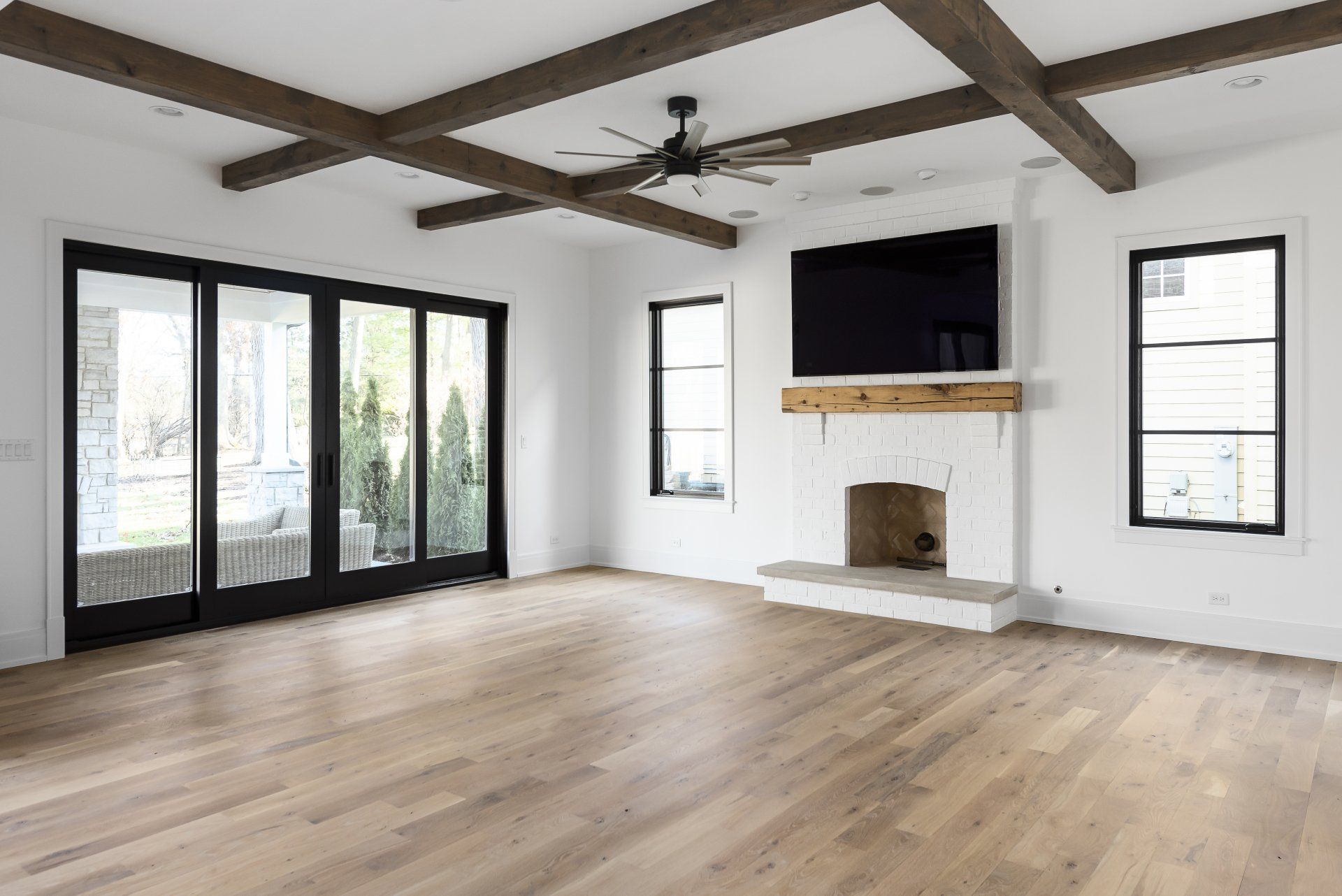 An empty living room with hardwood floors , a fireplace and a flat screen tv.
