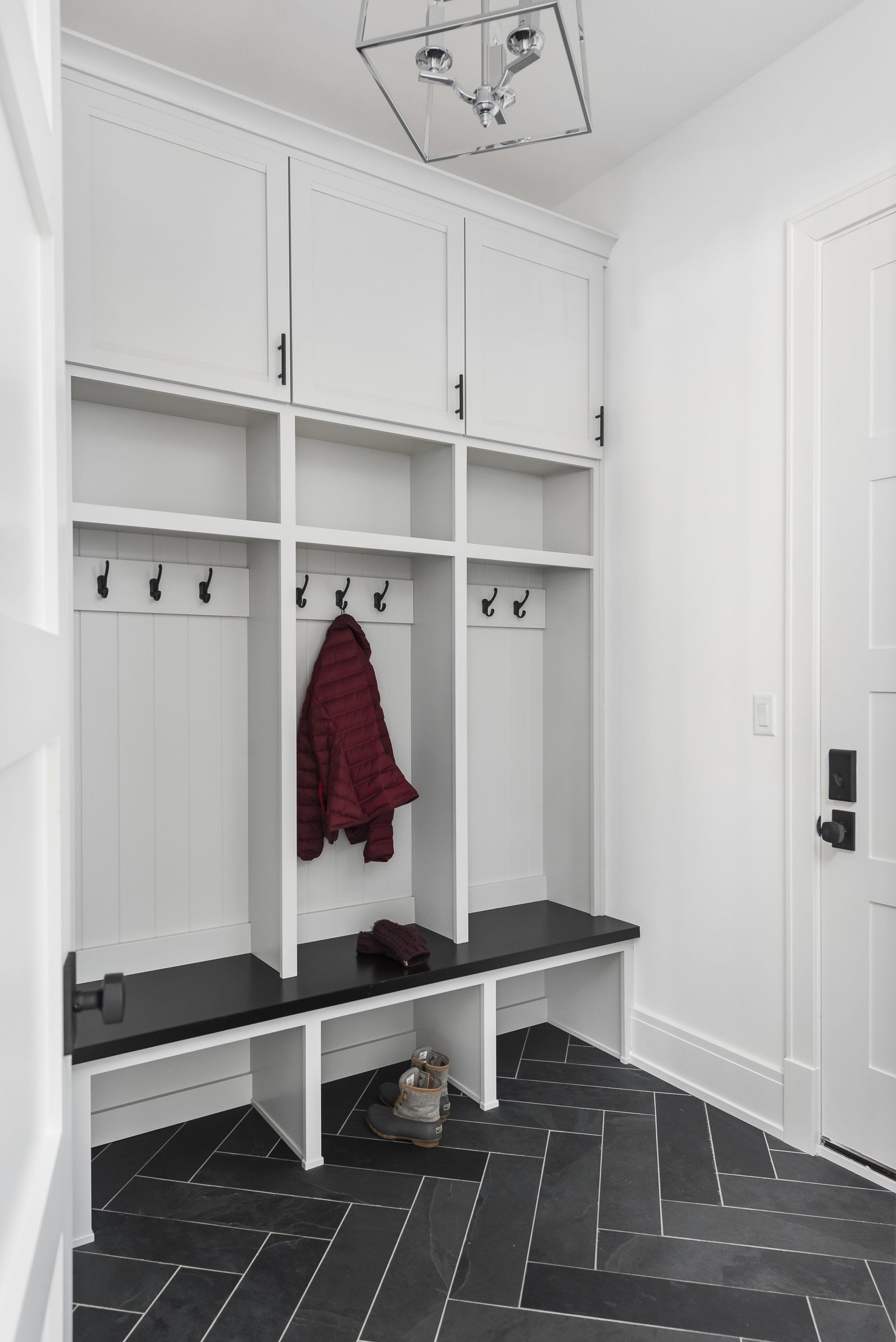 A cat is sitting on a bench in a mud room.
