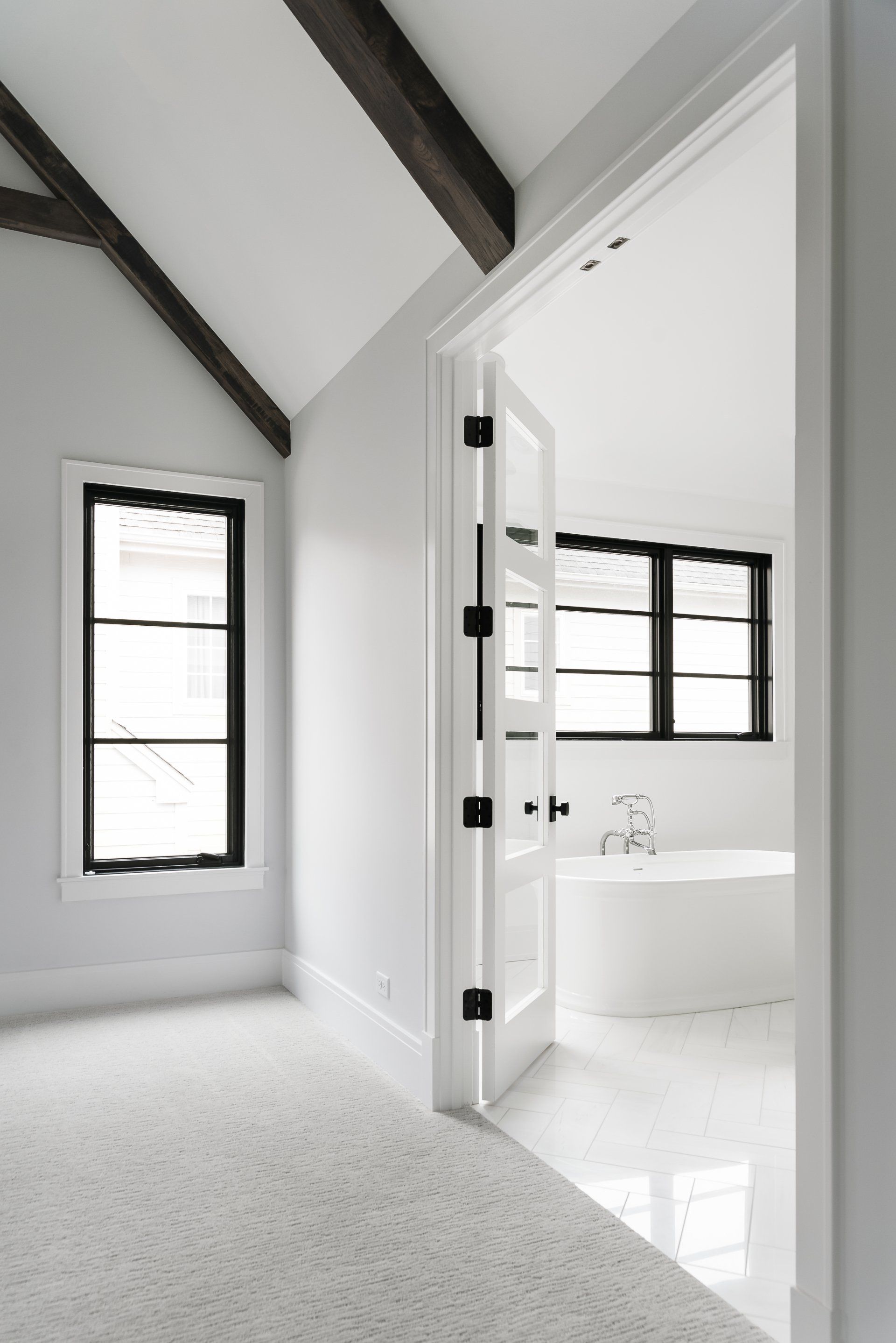 A bathroom with a bathtub and two windows in a house.