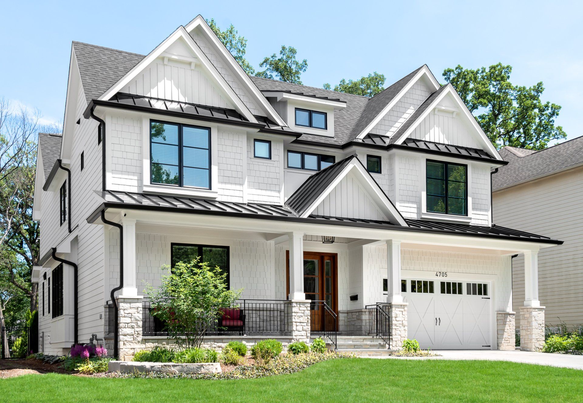 A large white house with a black roof and a large porch.