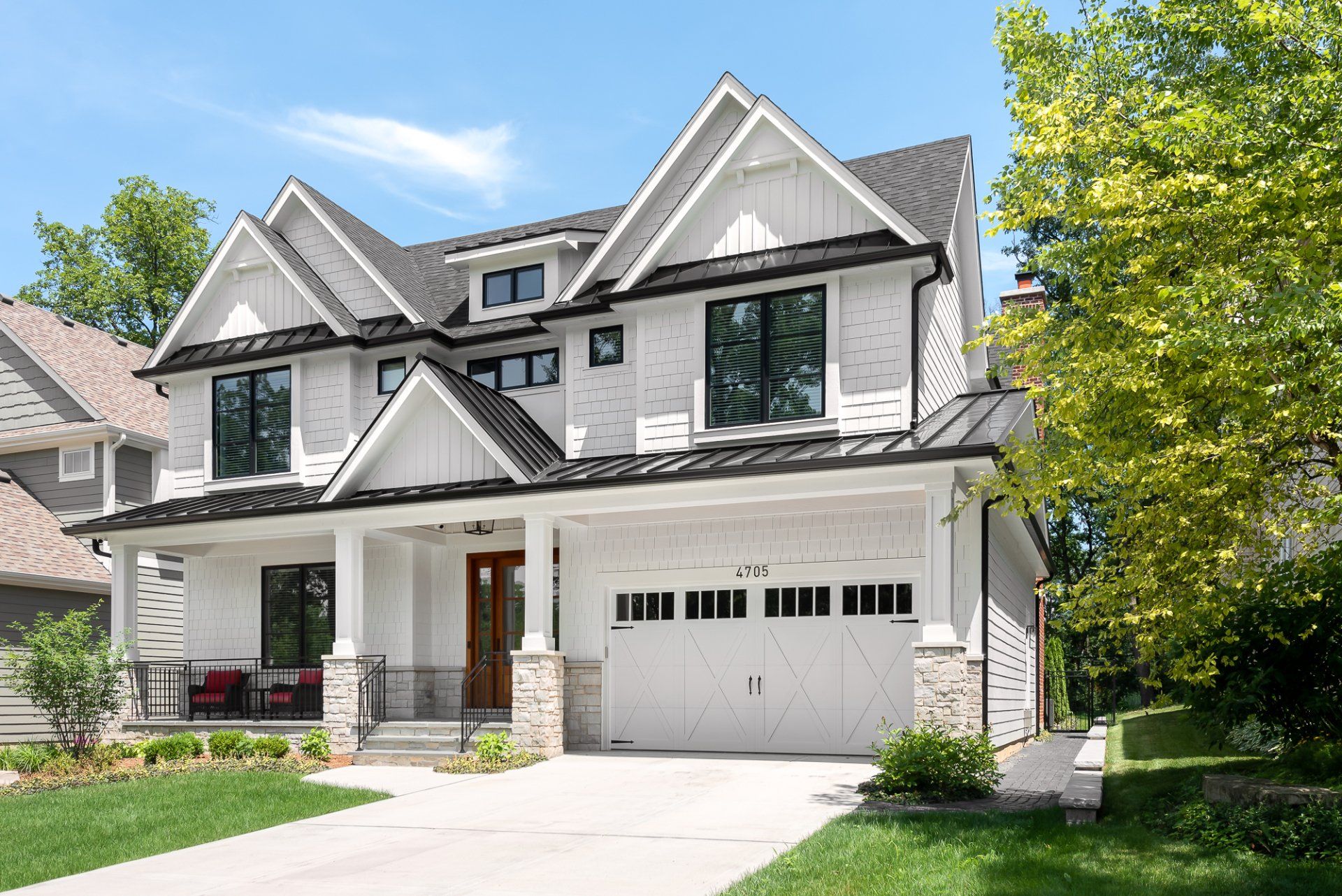 A large white house with a black roof and a large garage.