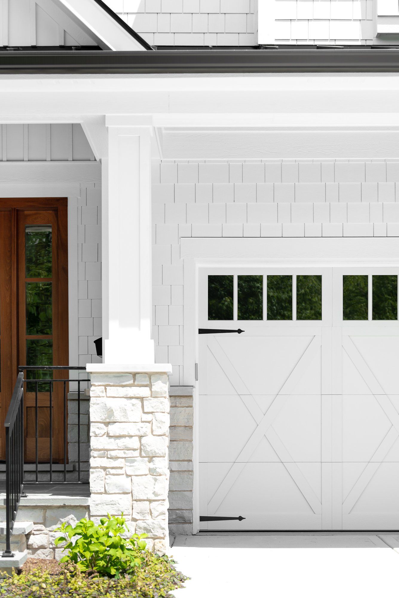 A white house with a white garage door and a wooden door.