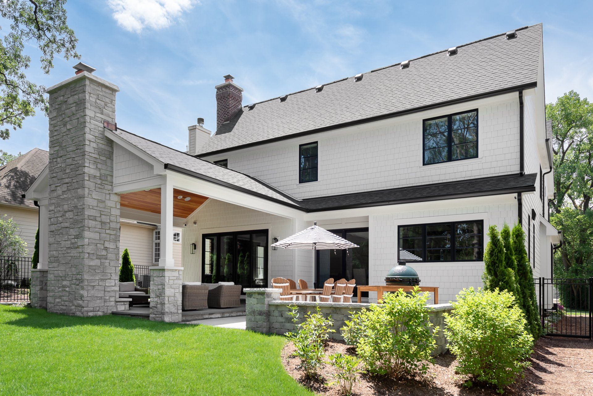 A large white house with a patio and umbrella in the backyard.