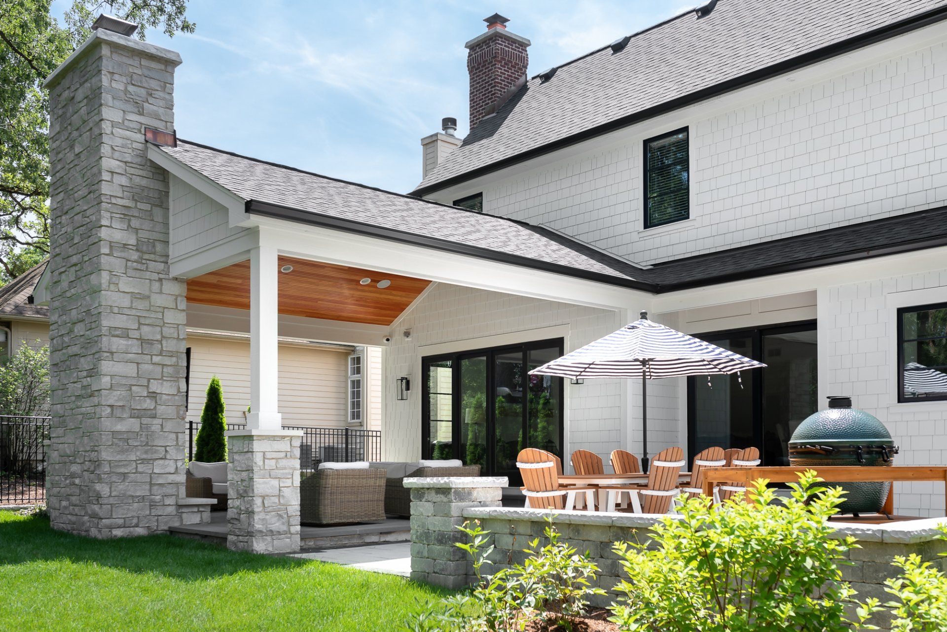 A large white house with a patio and umbrellas in front of it.