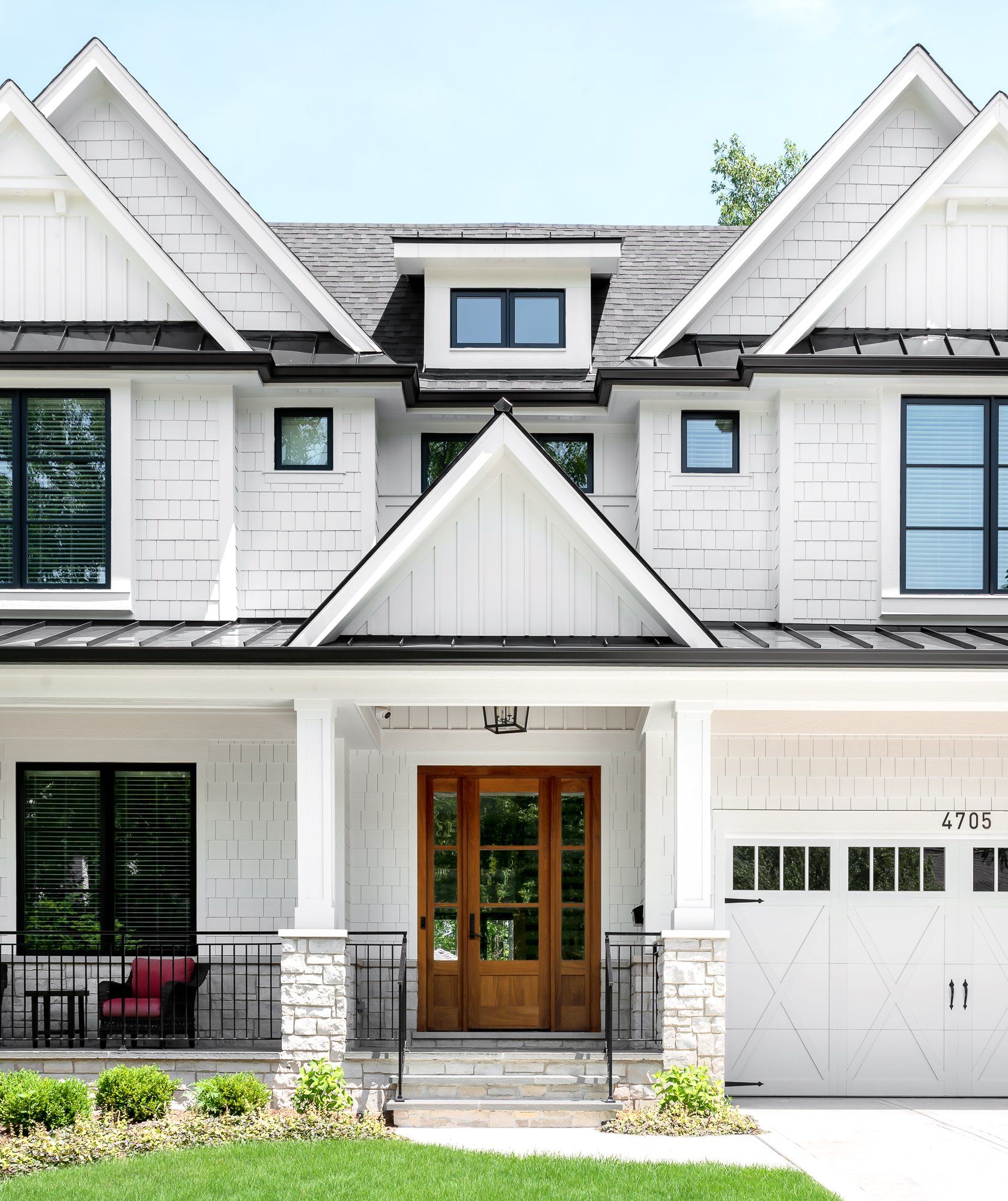 A large white house with a black roof and a large porch.