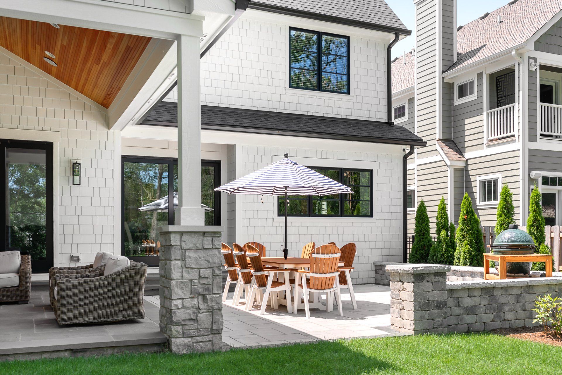 A large white house with a patio area with a table and chairs and an umbrella.