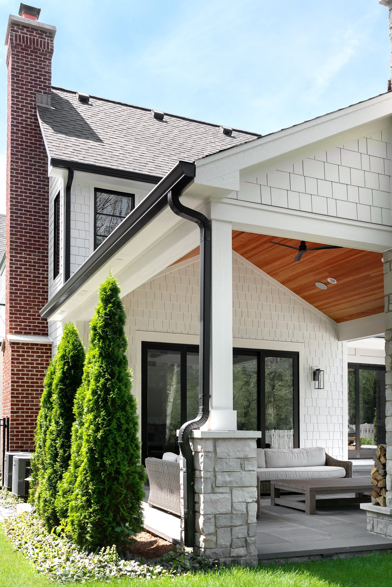 A white house with a large porch and a brick chimney.