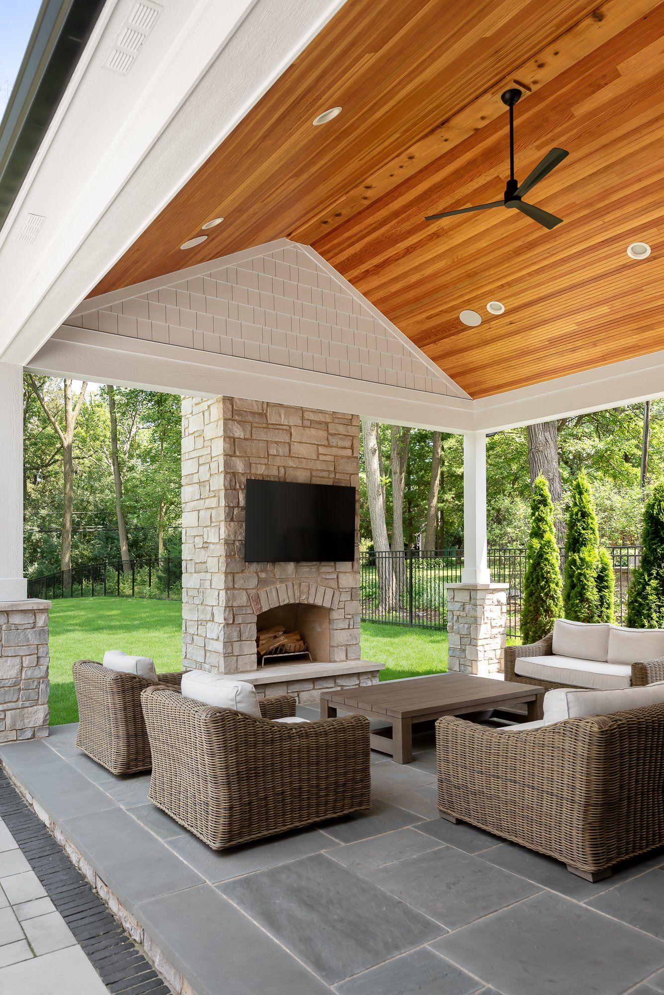 A patio with a fireplace , couch , chairs and a television.