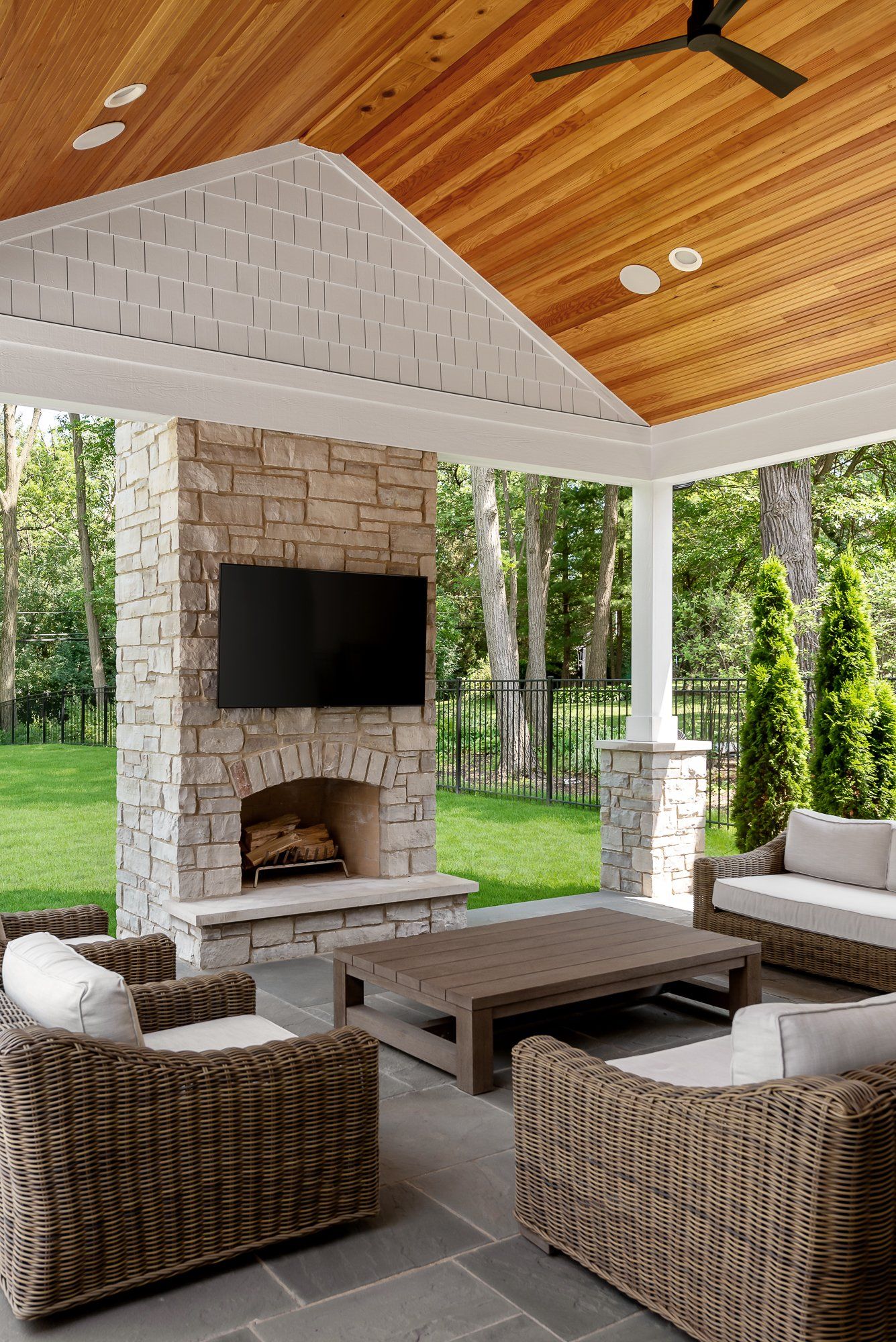 A living room with wicker furniture , a fireplace and a flat screen tv.