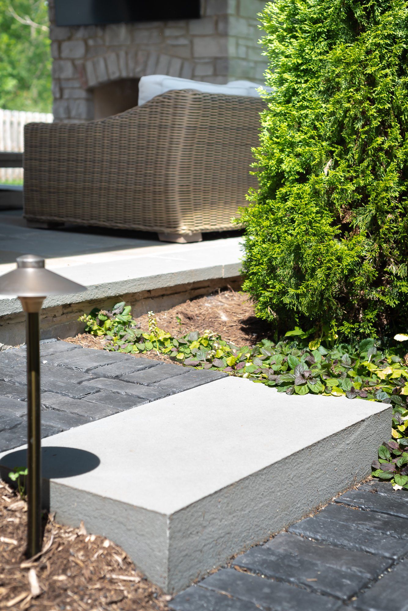 There is a wicker chair in the background and a bench in the foreground.