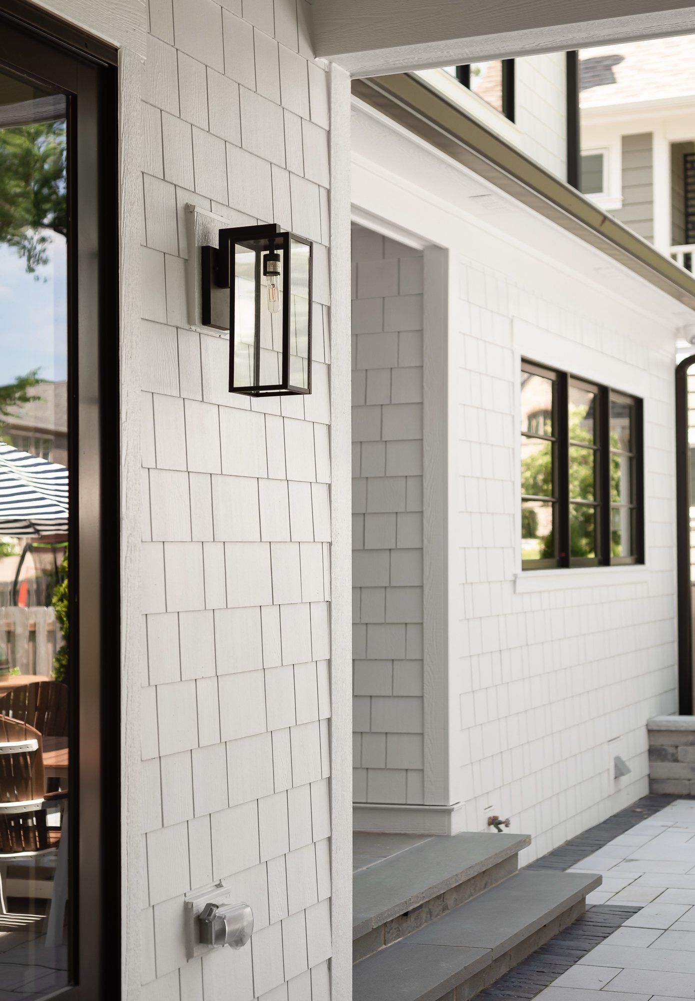 A white brick house with a black door and a light on the side of it.