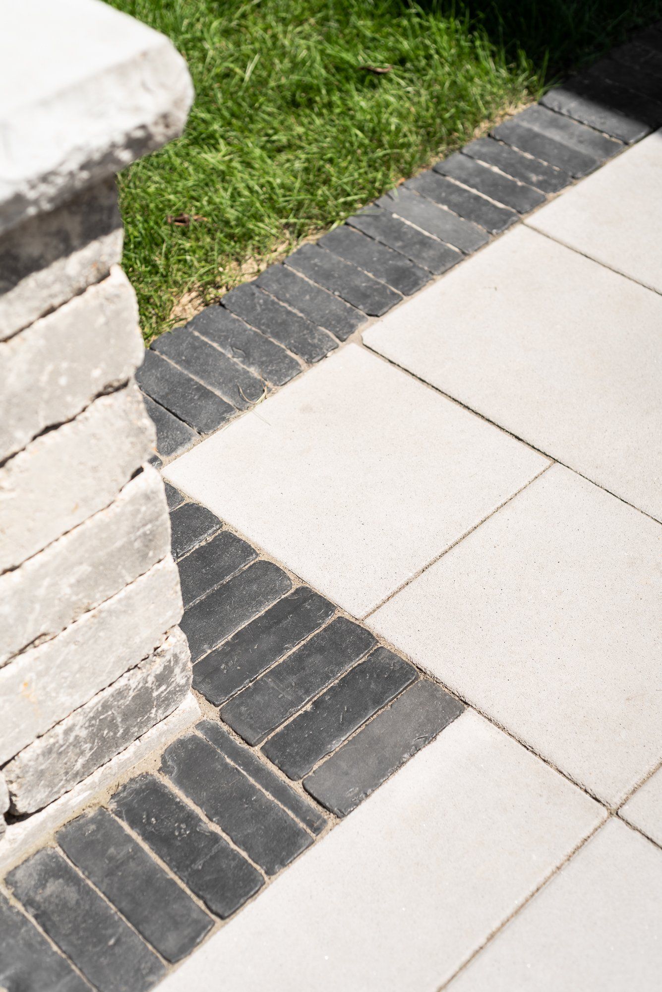 A close up of a patio with a black and white brick border.