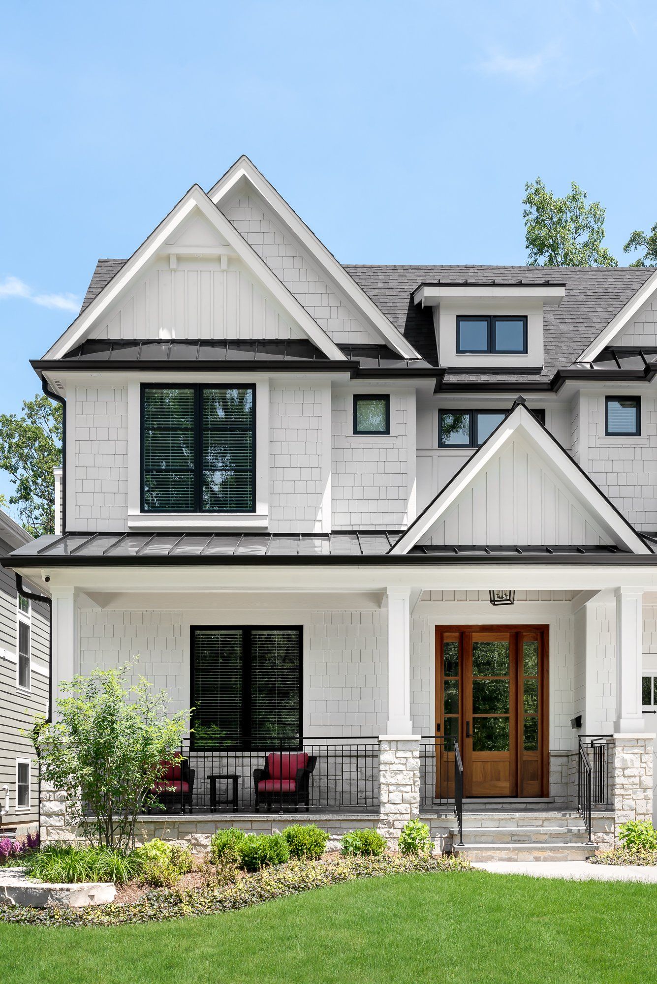 A large white house with a large porch and a lush green lawn.