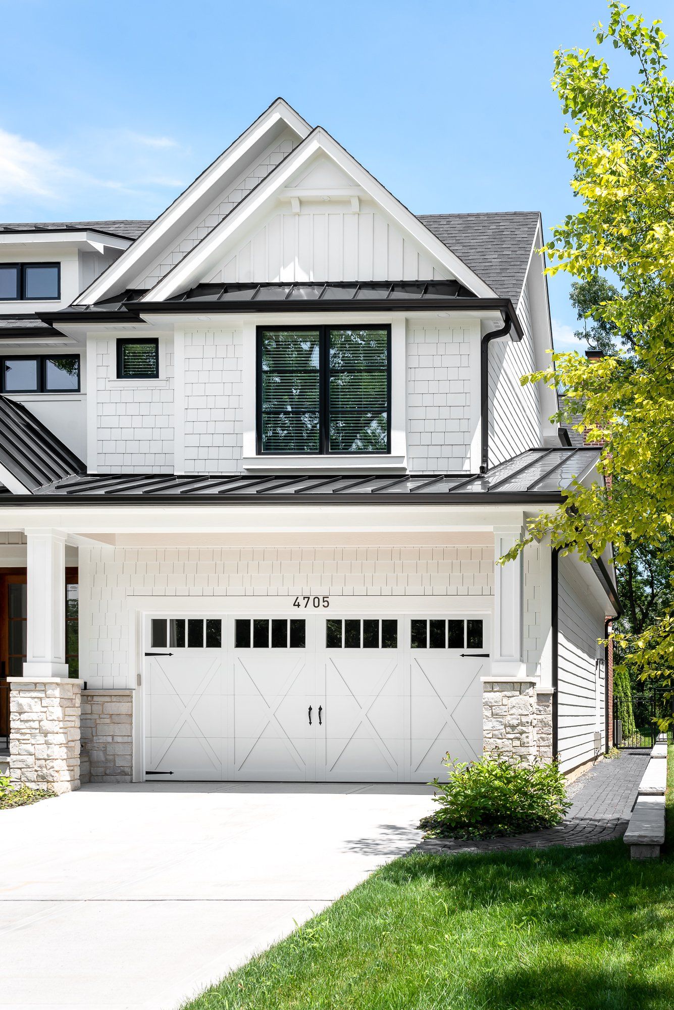 A white house with a black roof and a white garage door