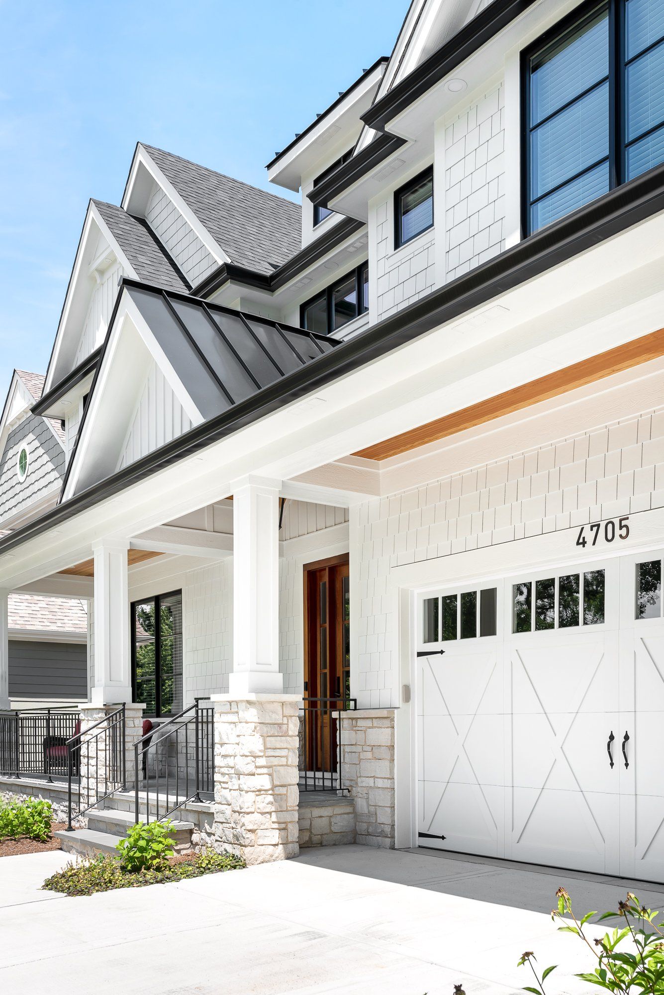 A white house with a black roof and a white garage door.
