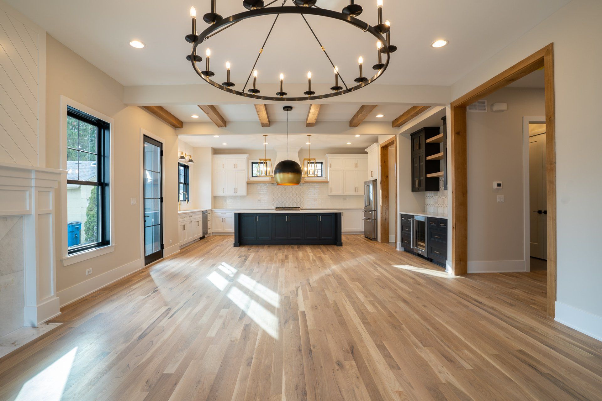 A large empty room with hardwood floors and a chandelier hanging from the ceiling.