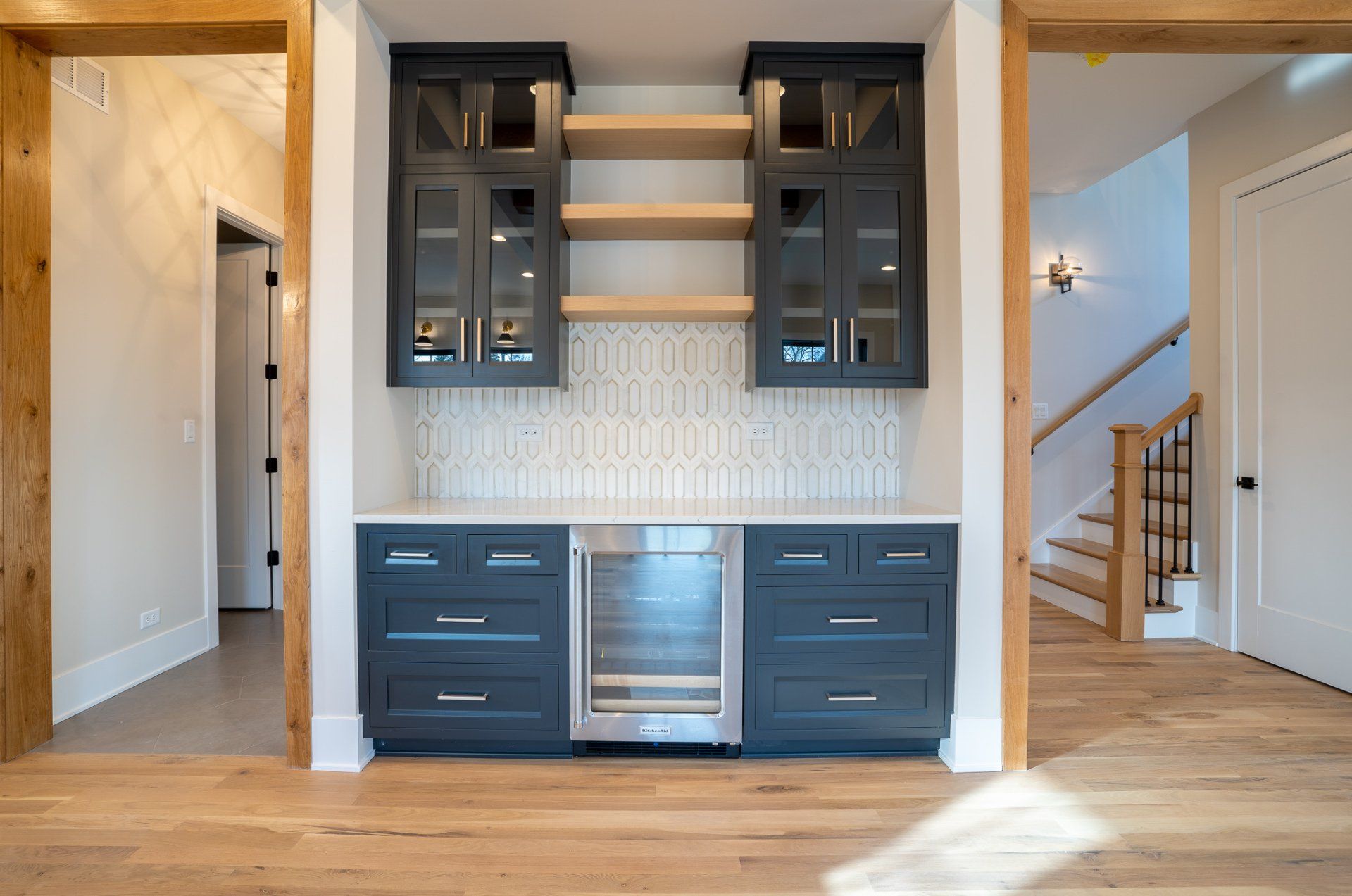 A kitchen with black cabinets and stainless steel appliances and a wine cooler.
