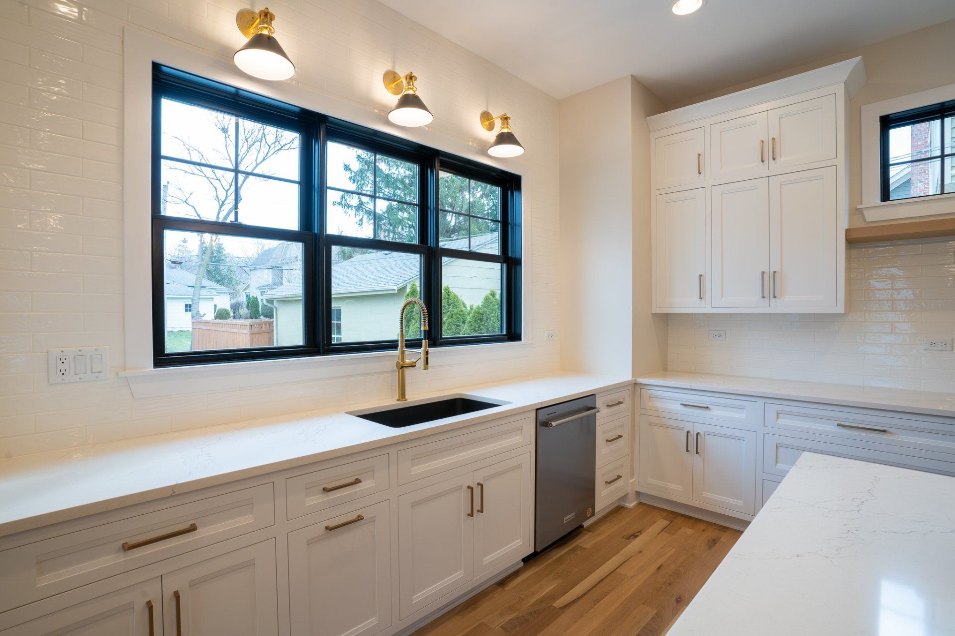 A kitchen with white cabinets , a sink , and a dishwasher.