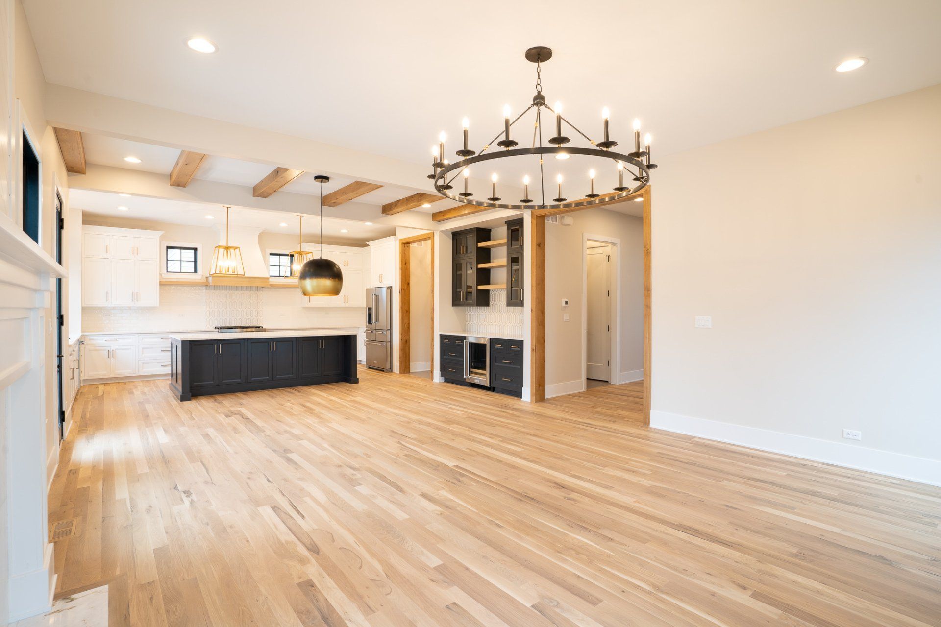 An empty living room with hardwood floors and a chandelier hanging from the ceiling.