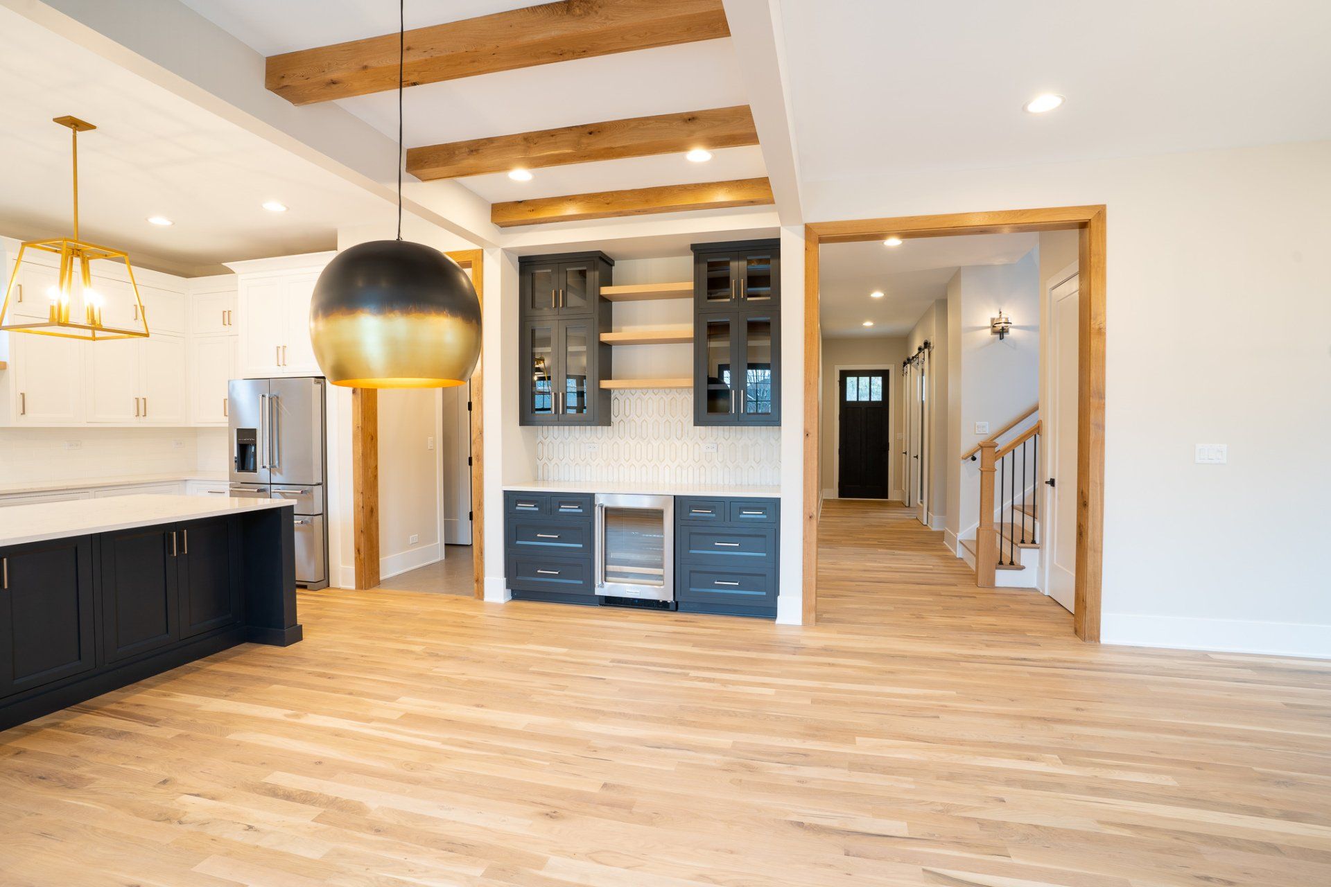 A kitchen and living room in a house with hardwood floors and stainless steel appliances.