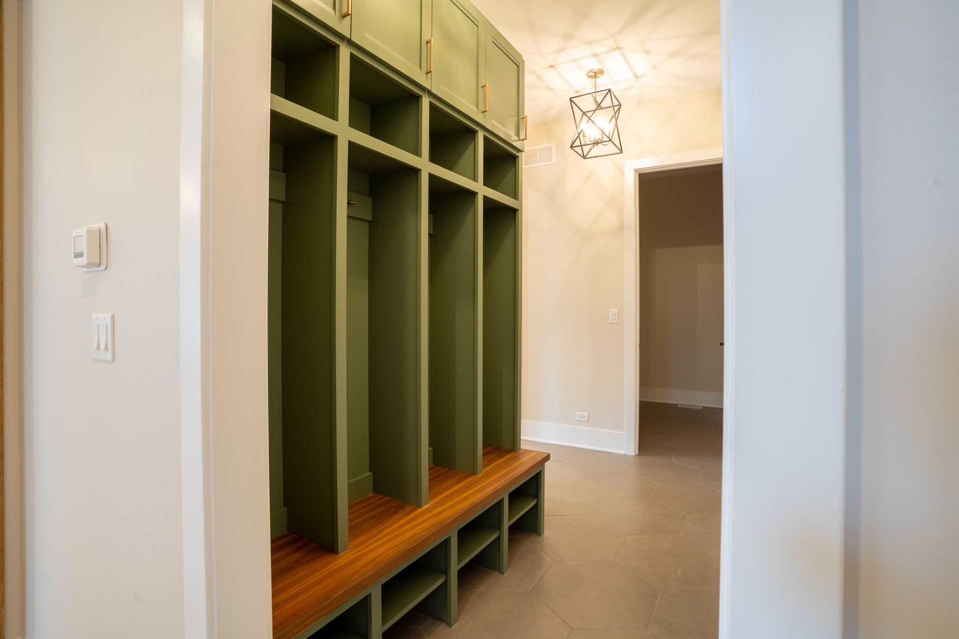 A mud room with green cabinets and a wooden bench.