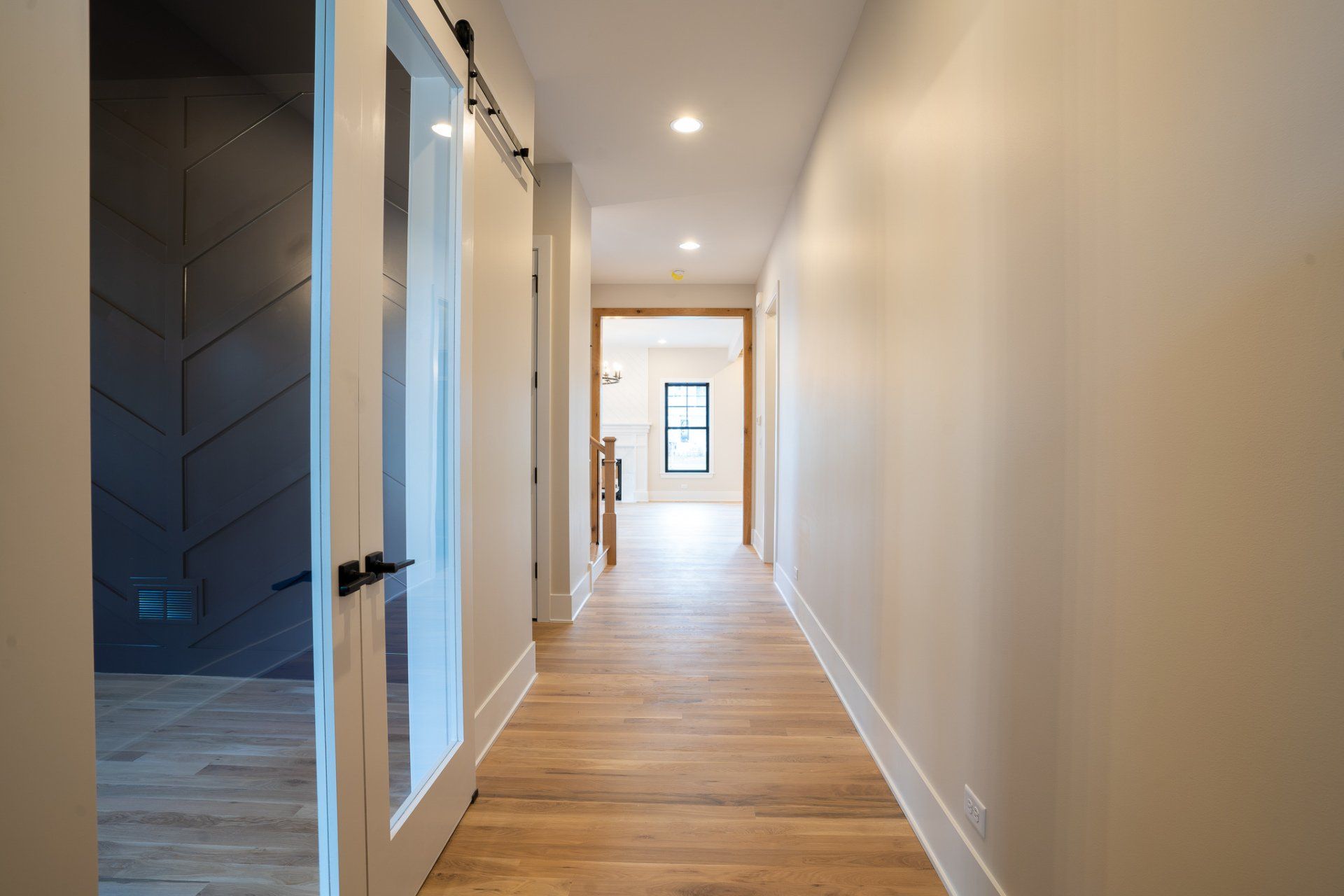 A long hallway with wooden floors and white walls in a house.