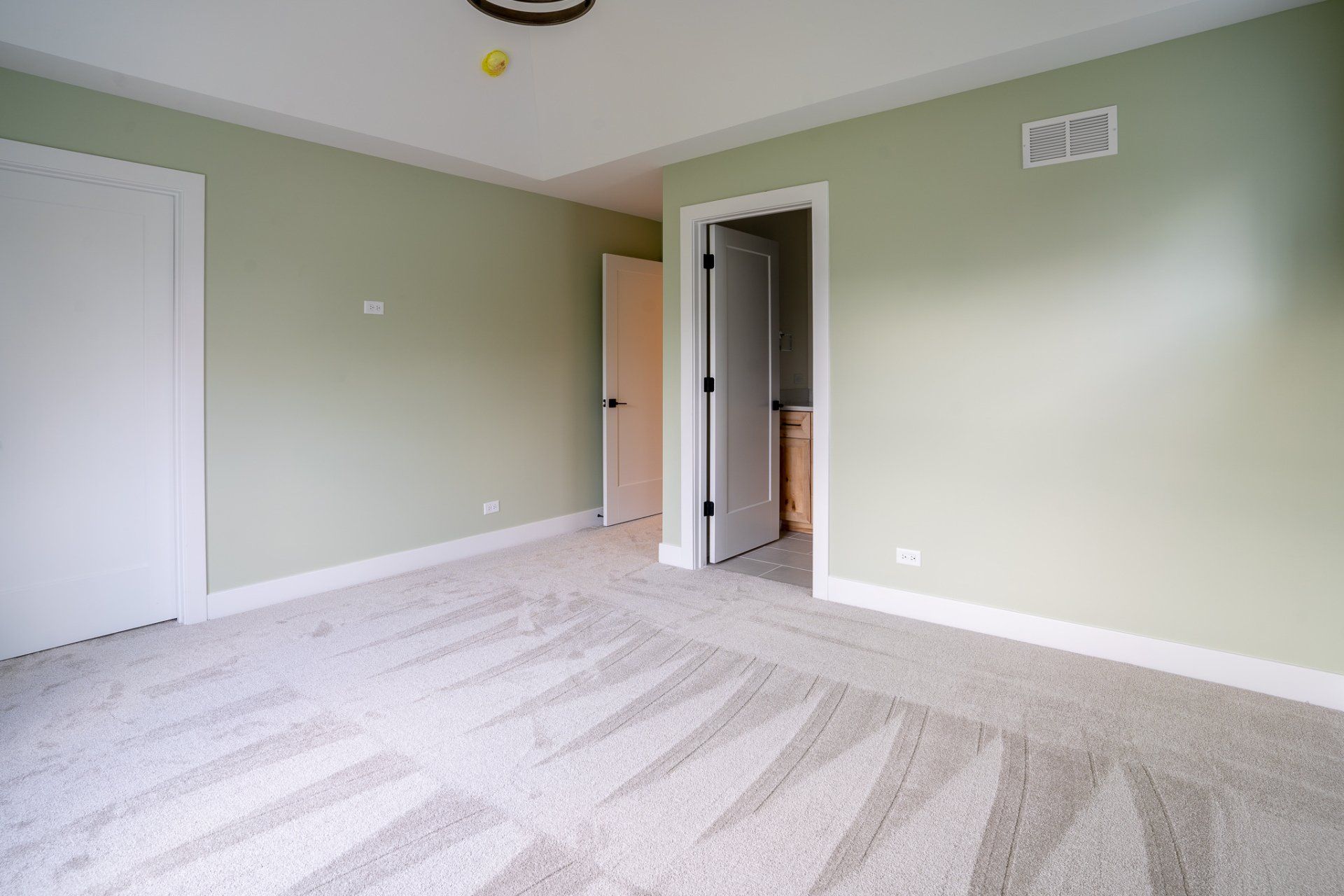 An empty bedroom with a carpeted floor and green walls.