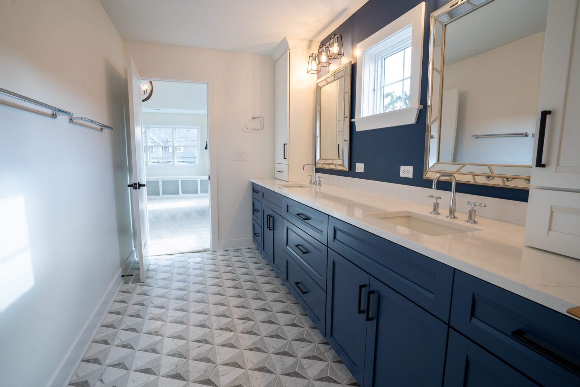 A bathroom with two sinks , two mirrors , and blue cabinets.