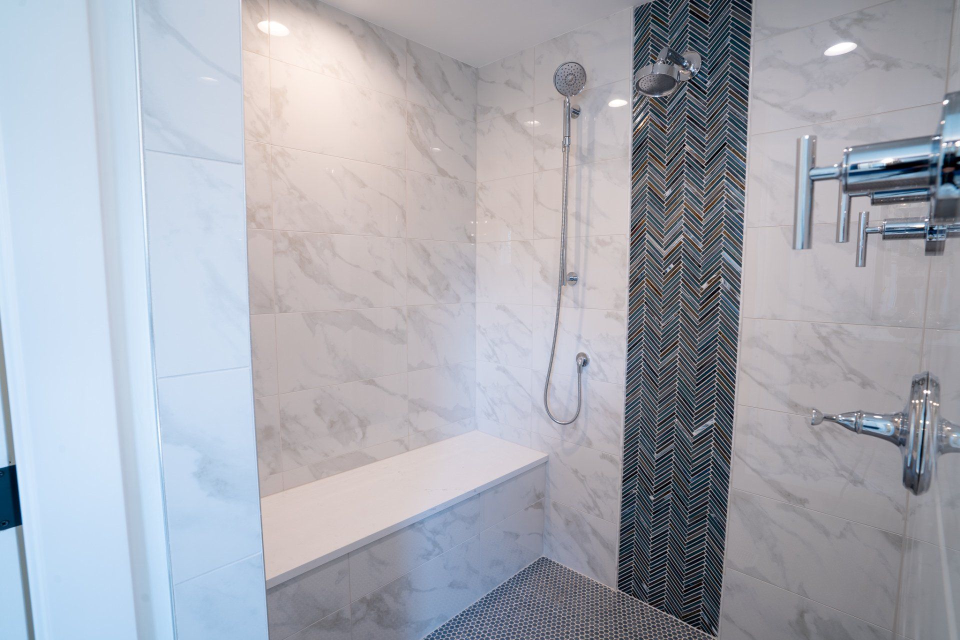 A bathroom with a walk in shower and a bench.