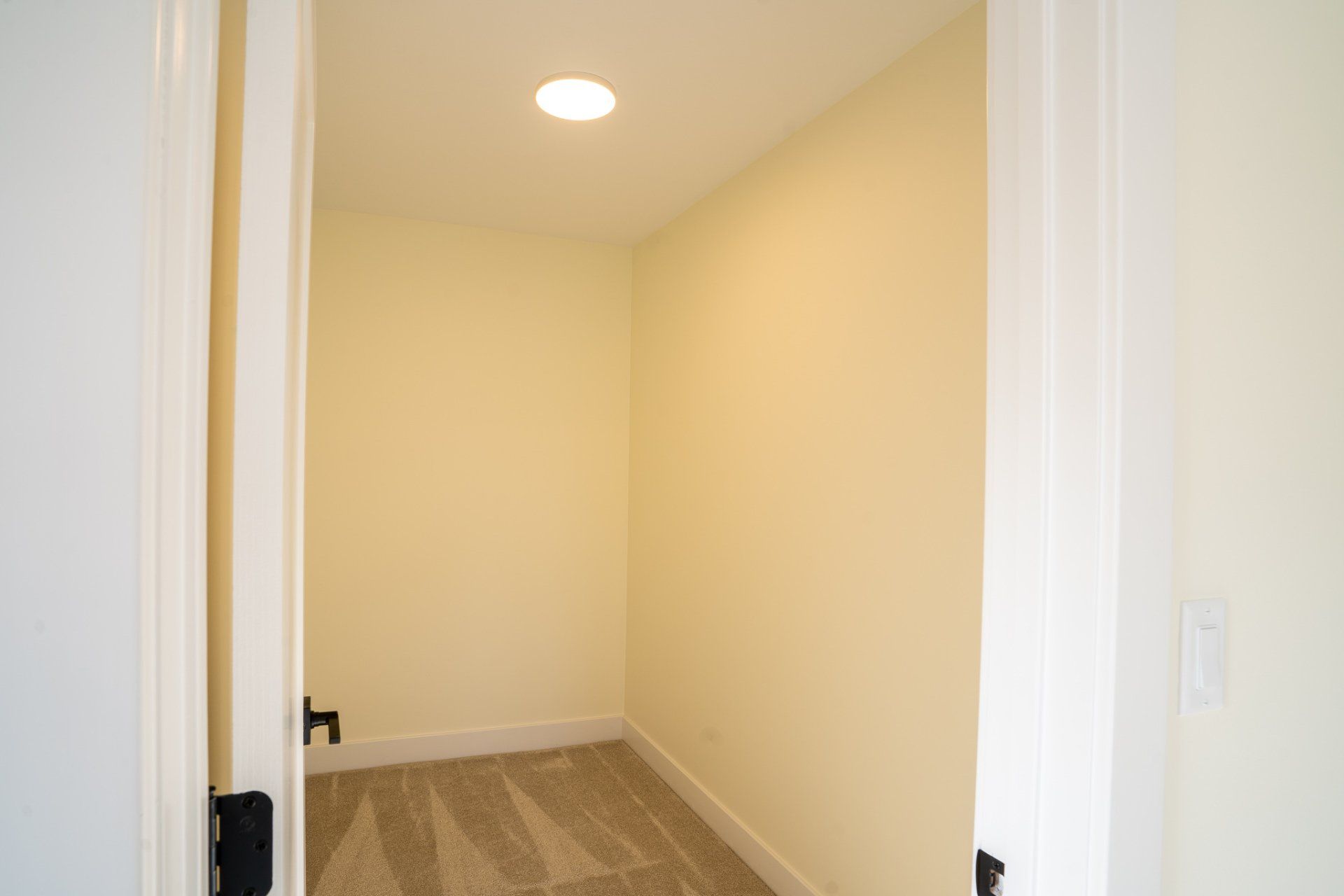 A small closet in a house with white walls and a light on the ceiling.