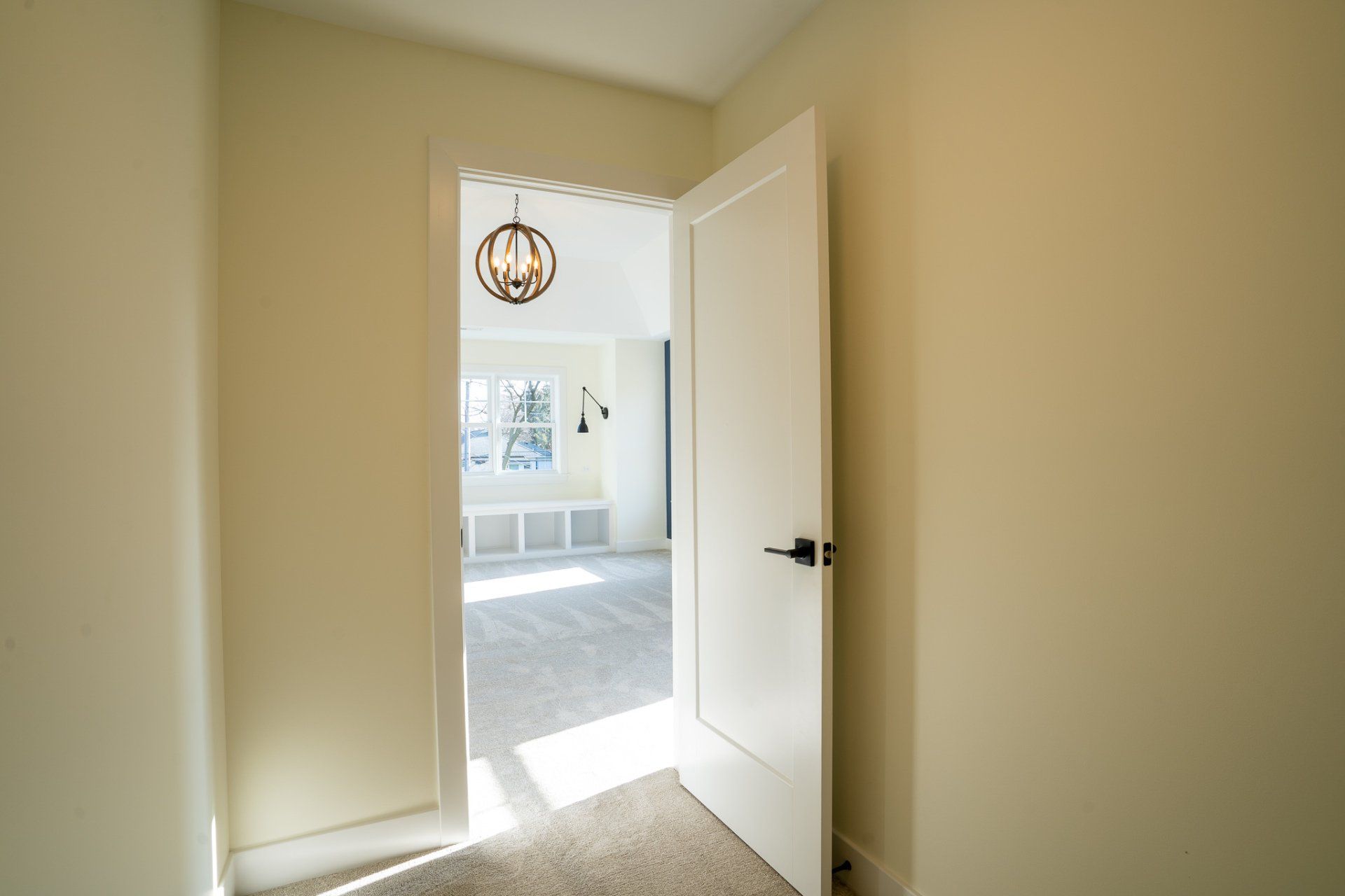 A white door is open to a room with a chandelier hanging from the ceiling.