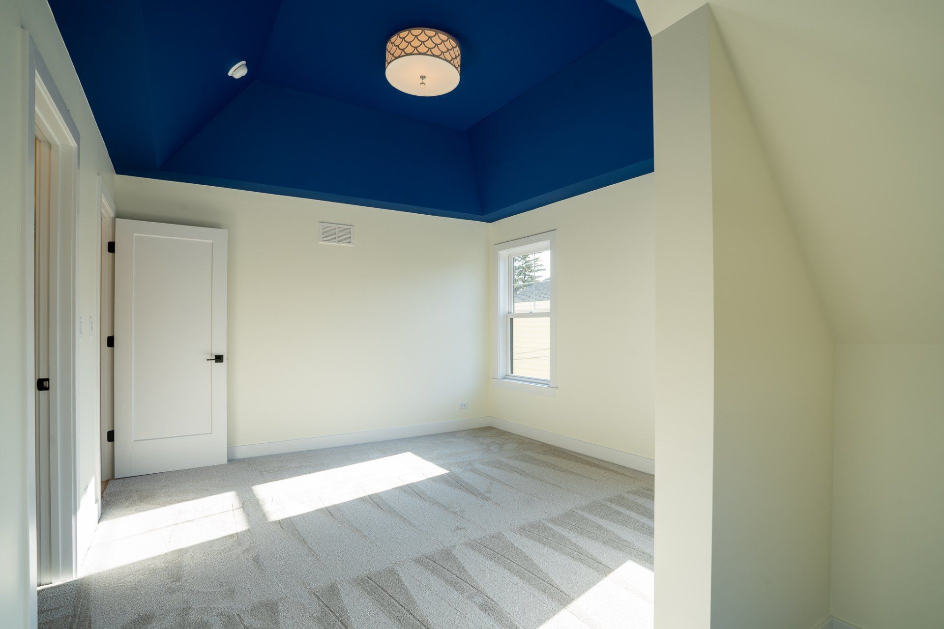 An empty room with a blue ceiling and a light fixture.