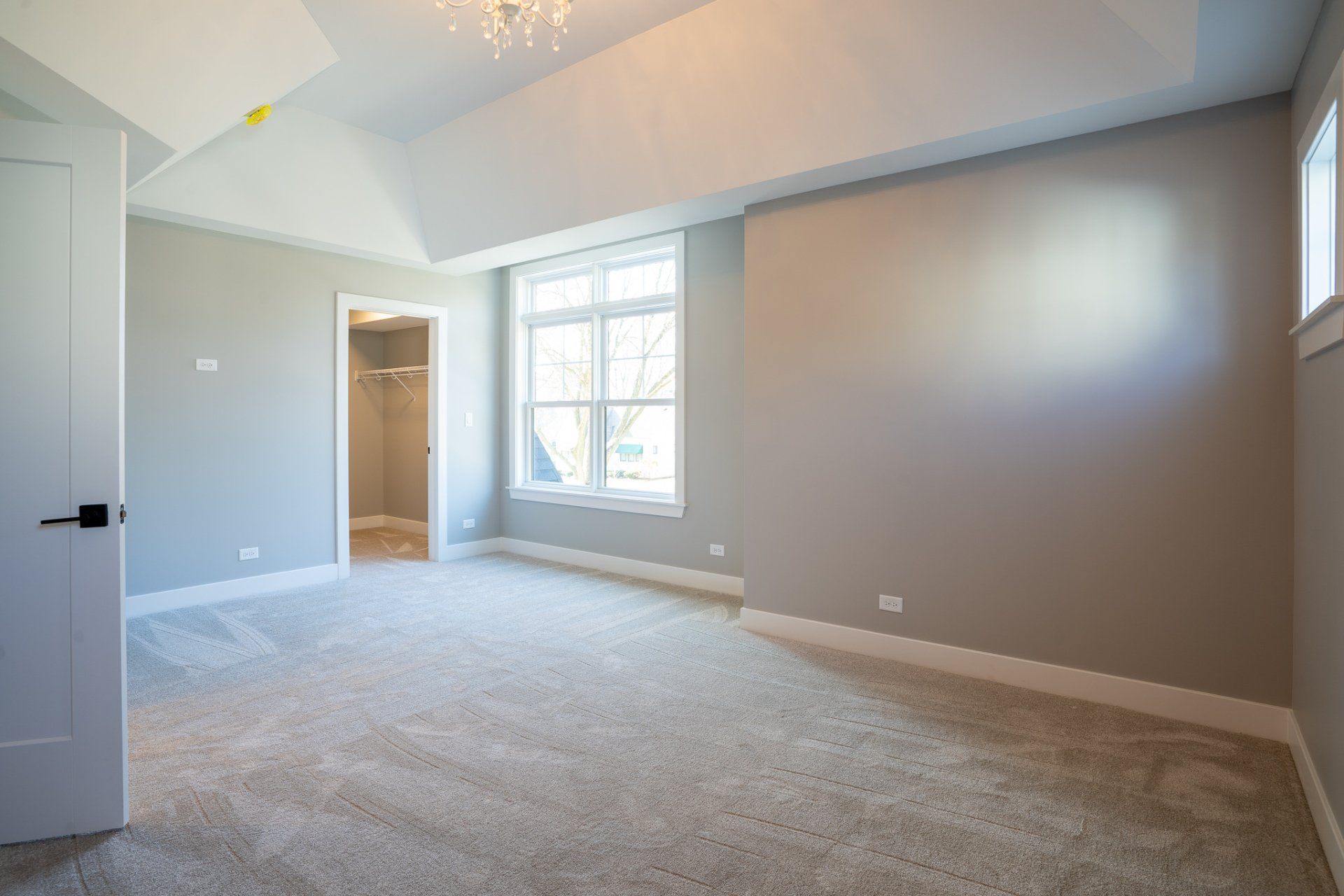 An empty bedroom with a large window and a walk in closet.