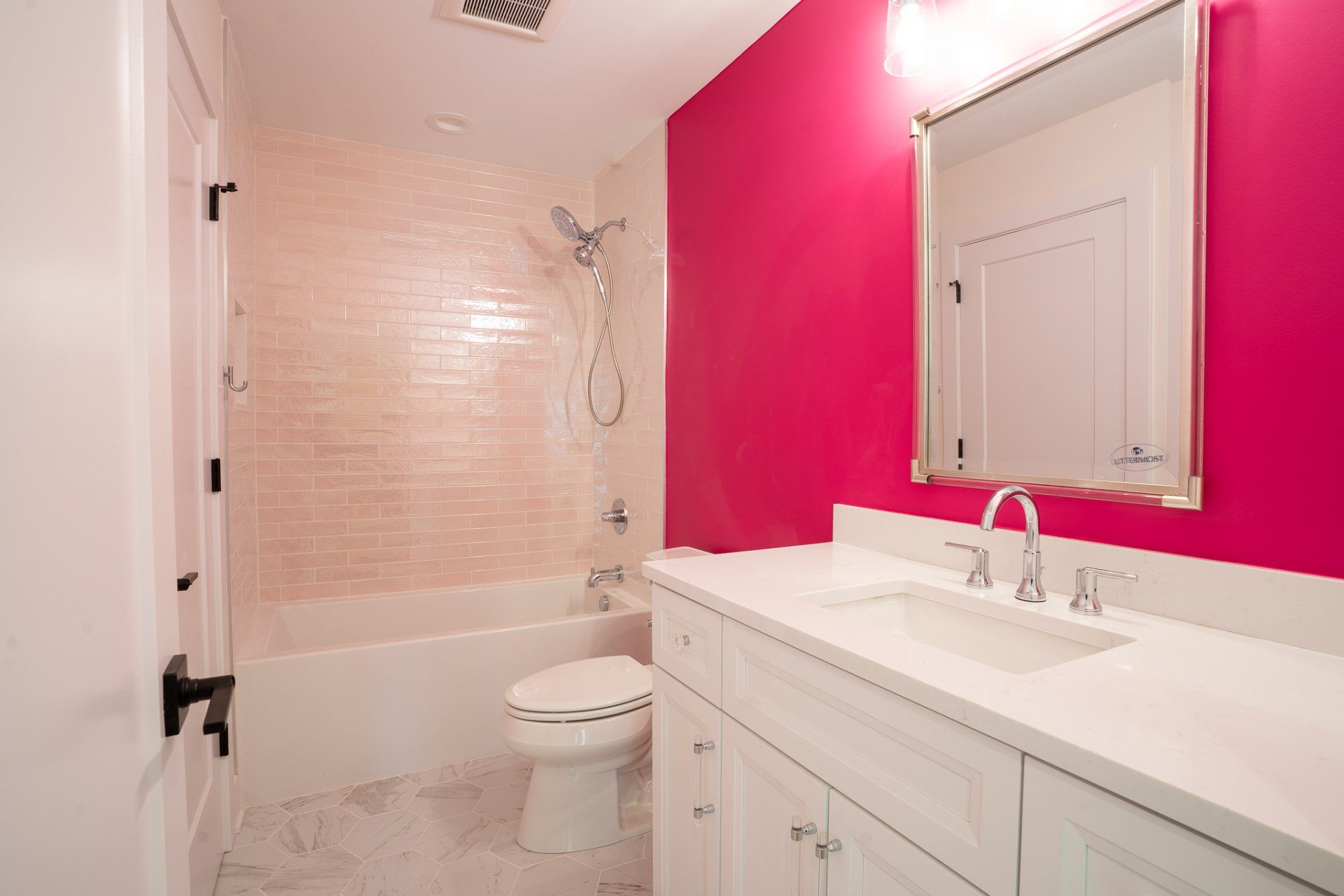 A bathroom with pink walls , a toilet , a sink , and a mirror.