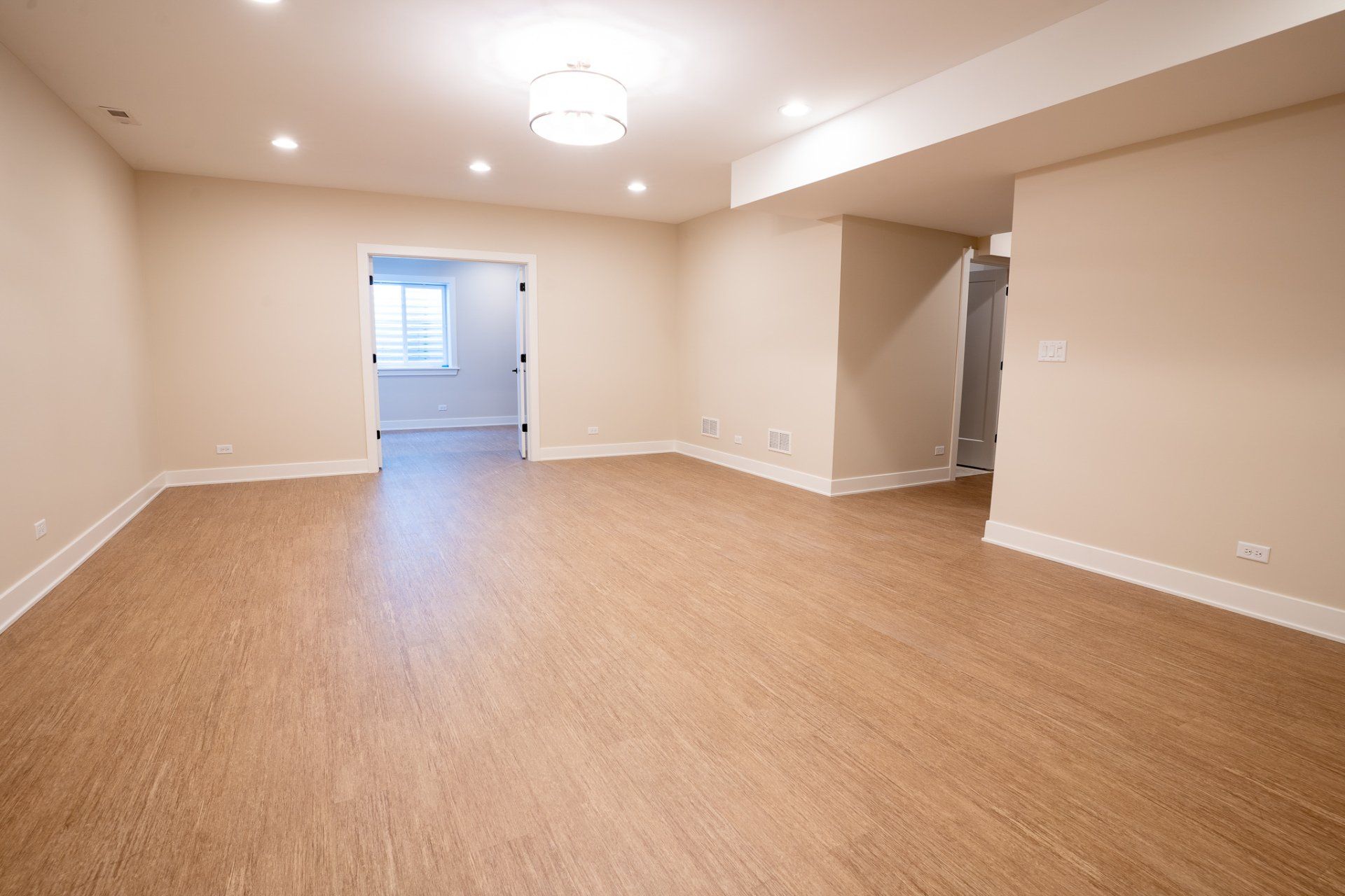 An empty room with a wooden floor and beige walls