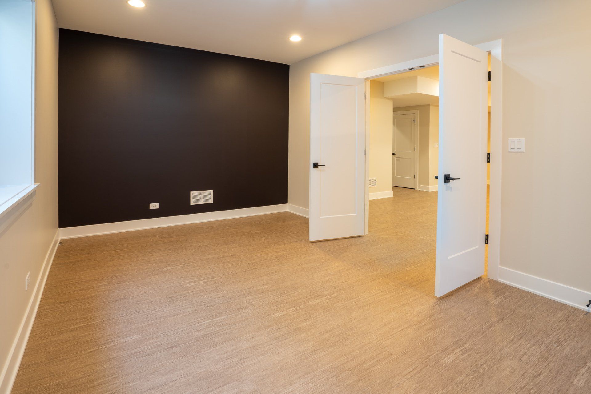 An empty basement with a brown carpet and a black wall.