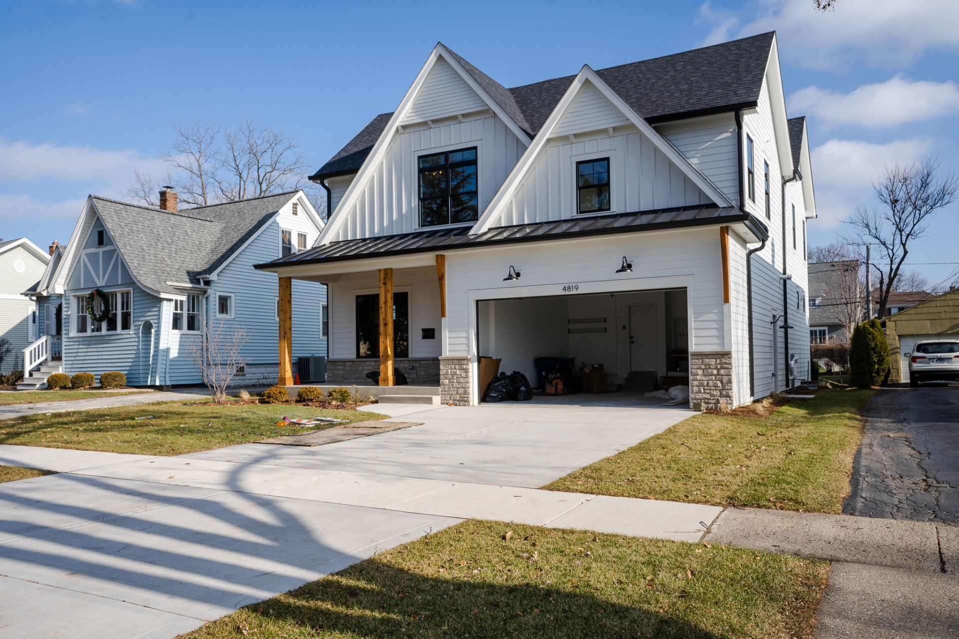 A white house with a garage and a car parked in front of it.