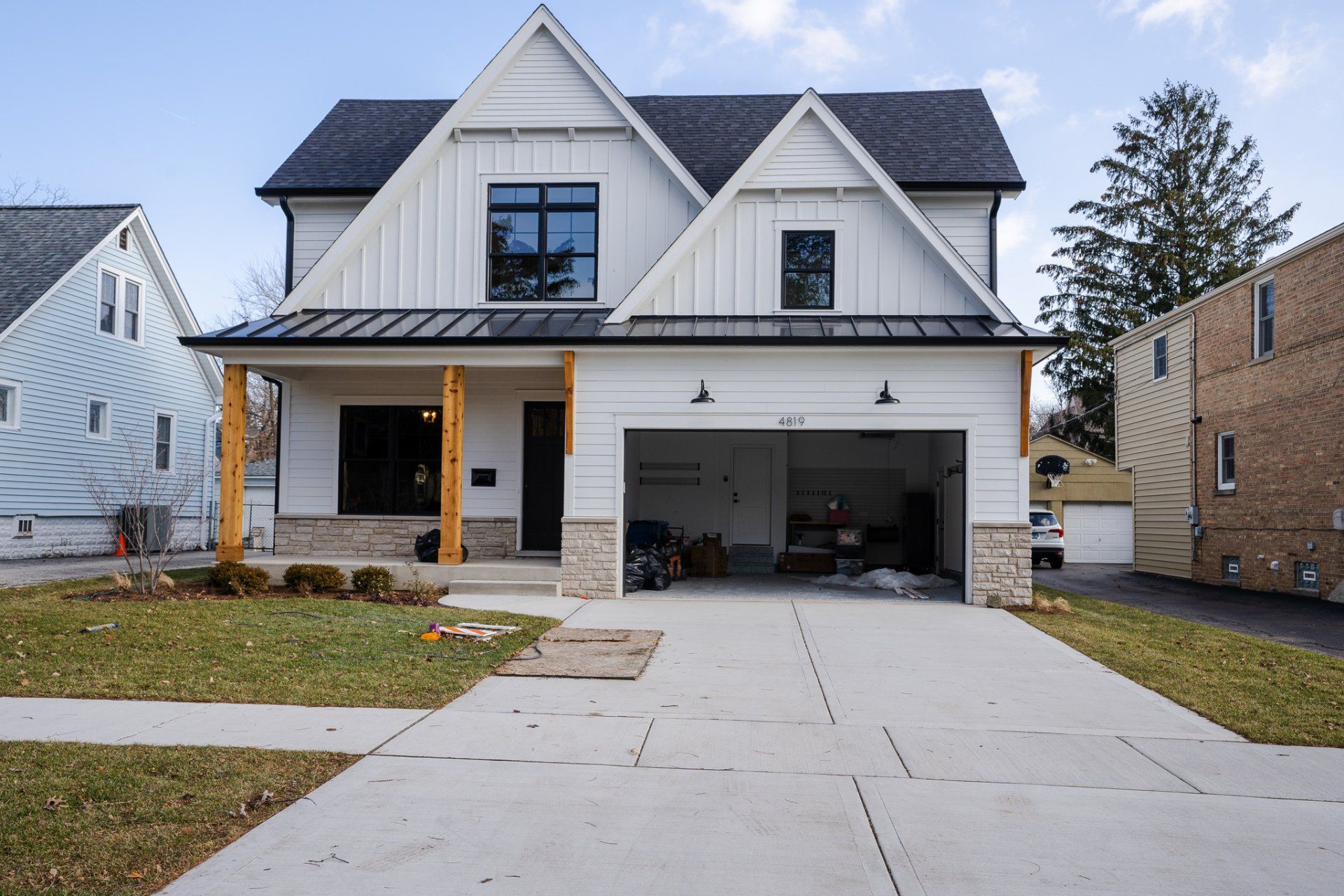 A white house with a black roof and a large garage.