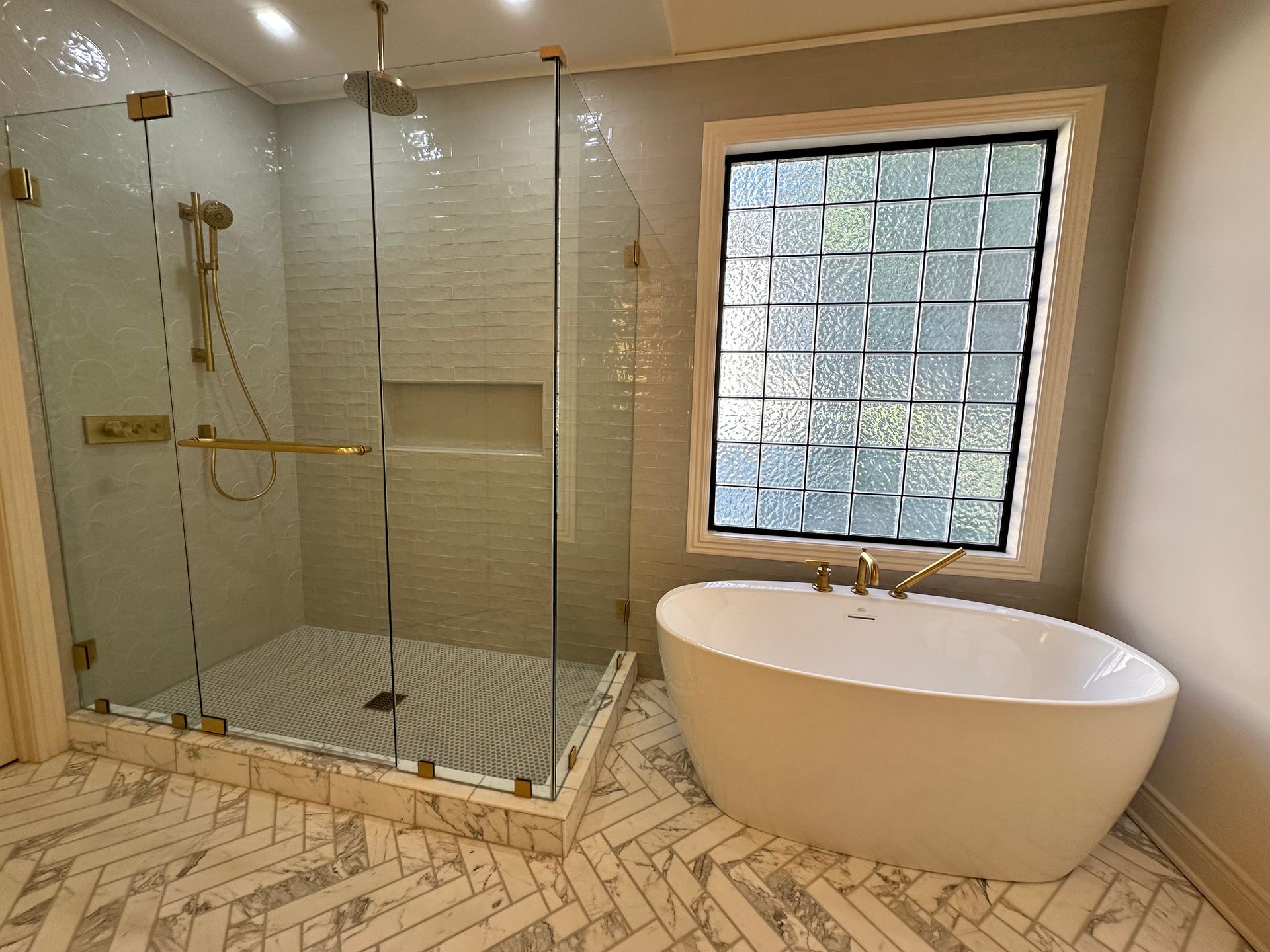Bathroom with blue tile shower, wood vanity, and oval mirror.
