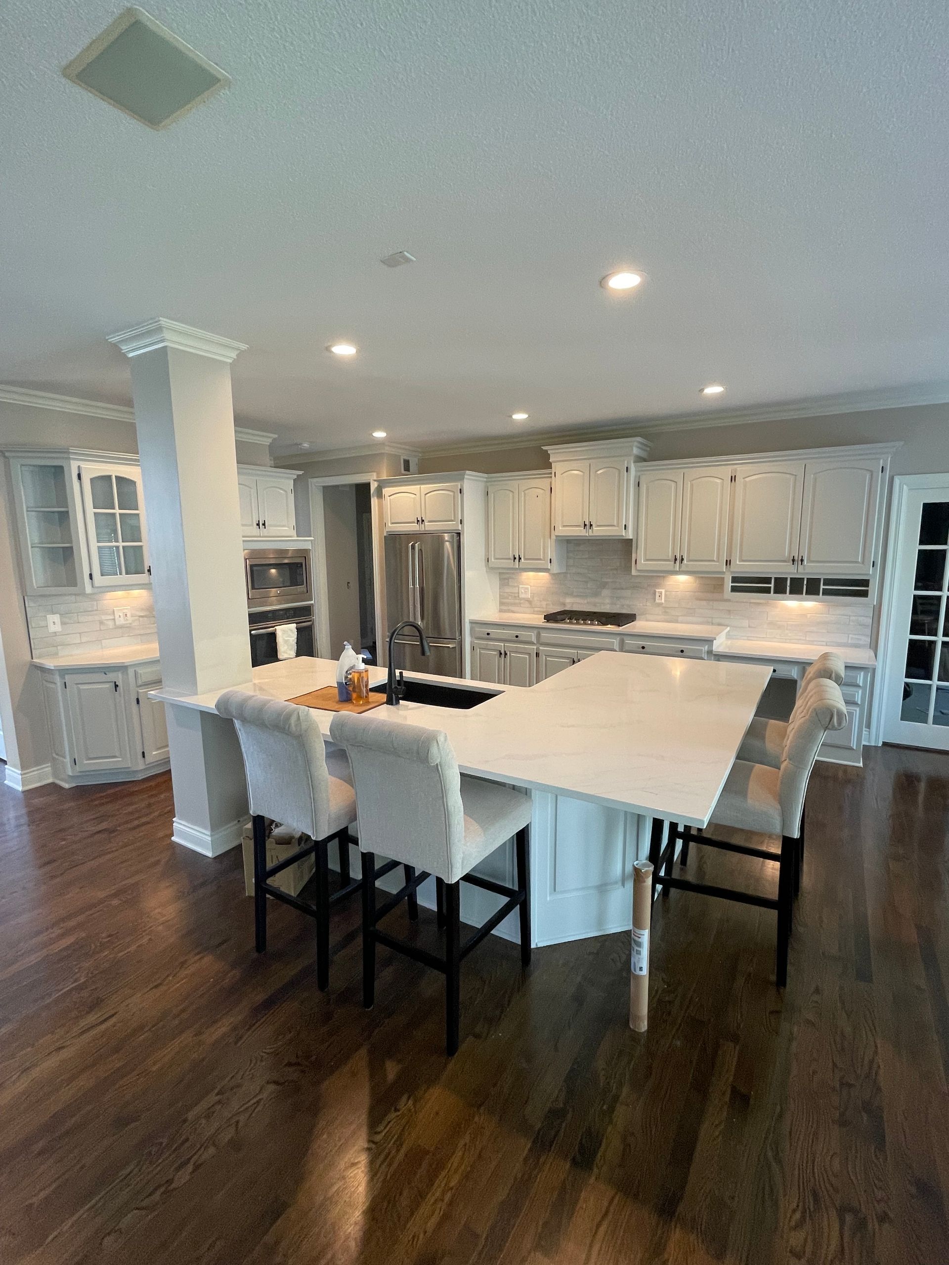 Hallway under construction with stairs, wood flooring, and exposed electrical wires.