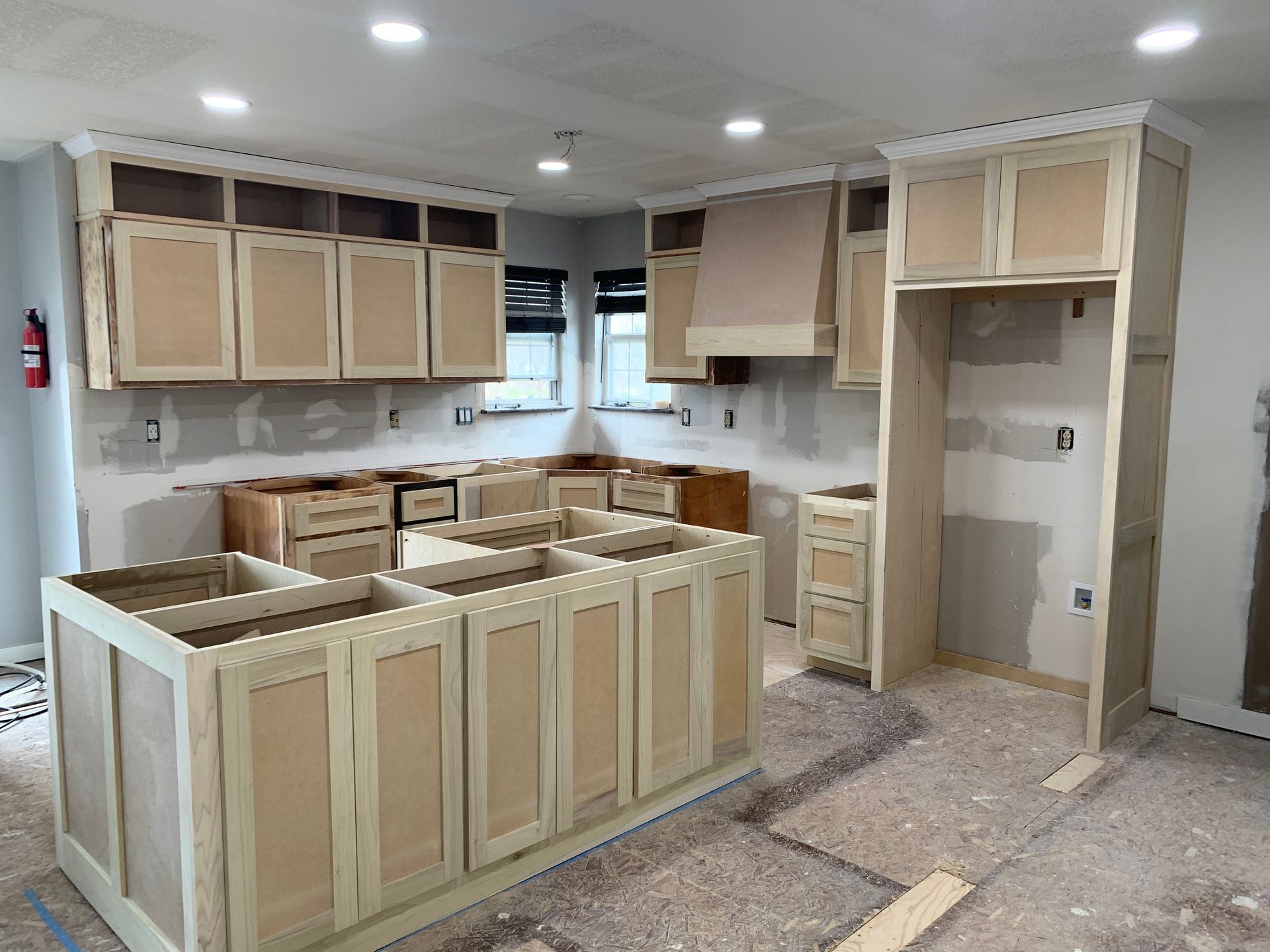 Person installing insulation in an attic, wearing a hard hat, gloves, and a mask.